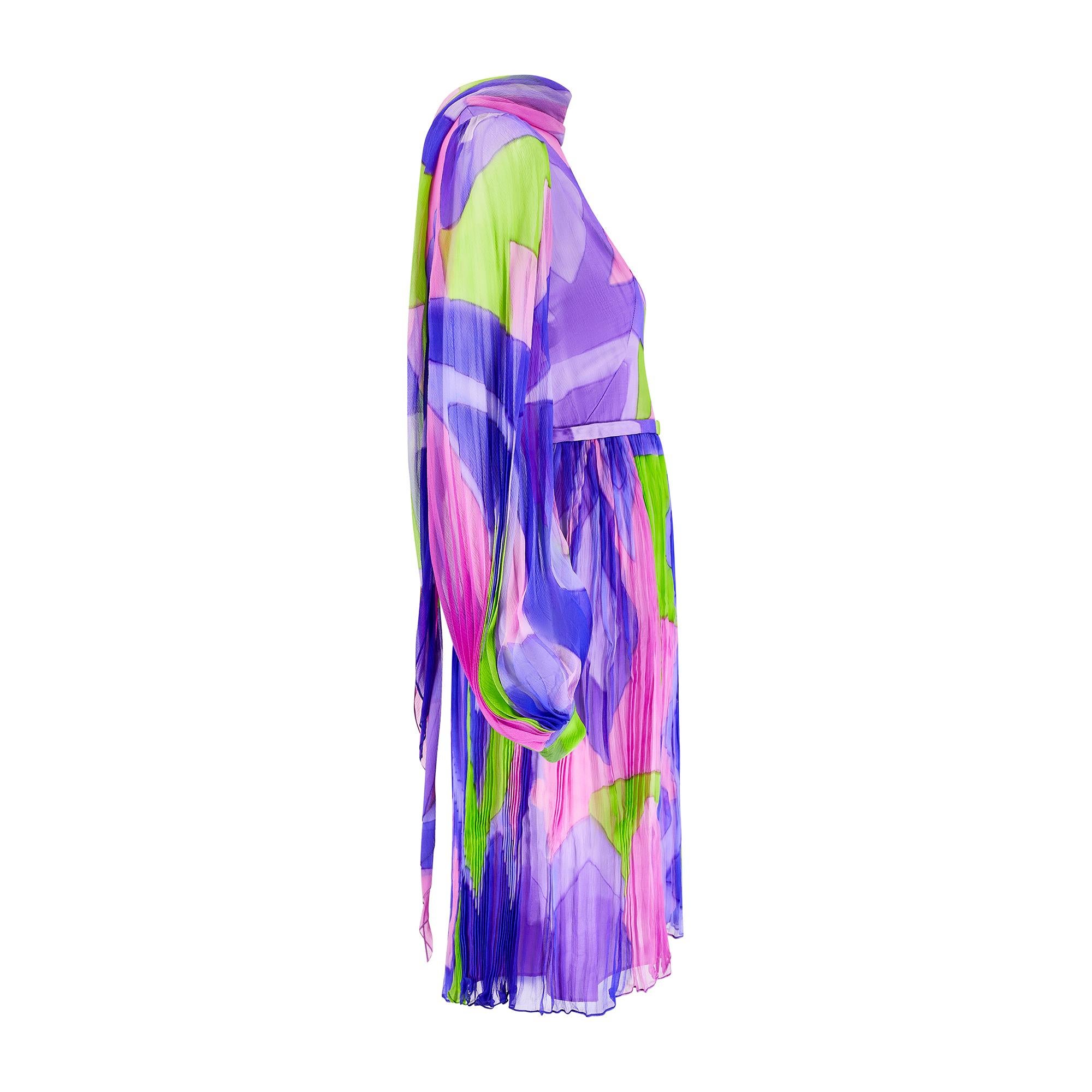 This flamboyant 1960s British couture dress is crafted from silk chiffon hand-dyed with a swirling, psychedelic pattern in lilac, pink and lime green. The couturier is unknown as the labels have been lost with the passage of time.  This bell-sleeve,