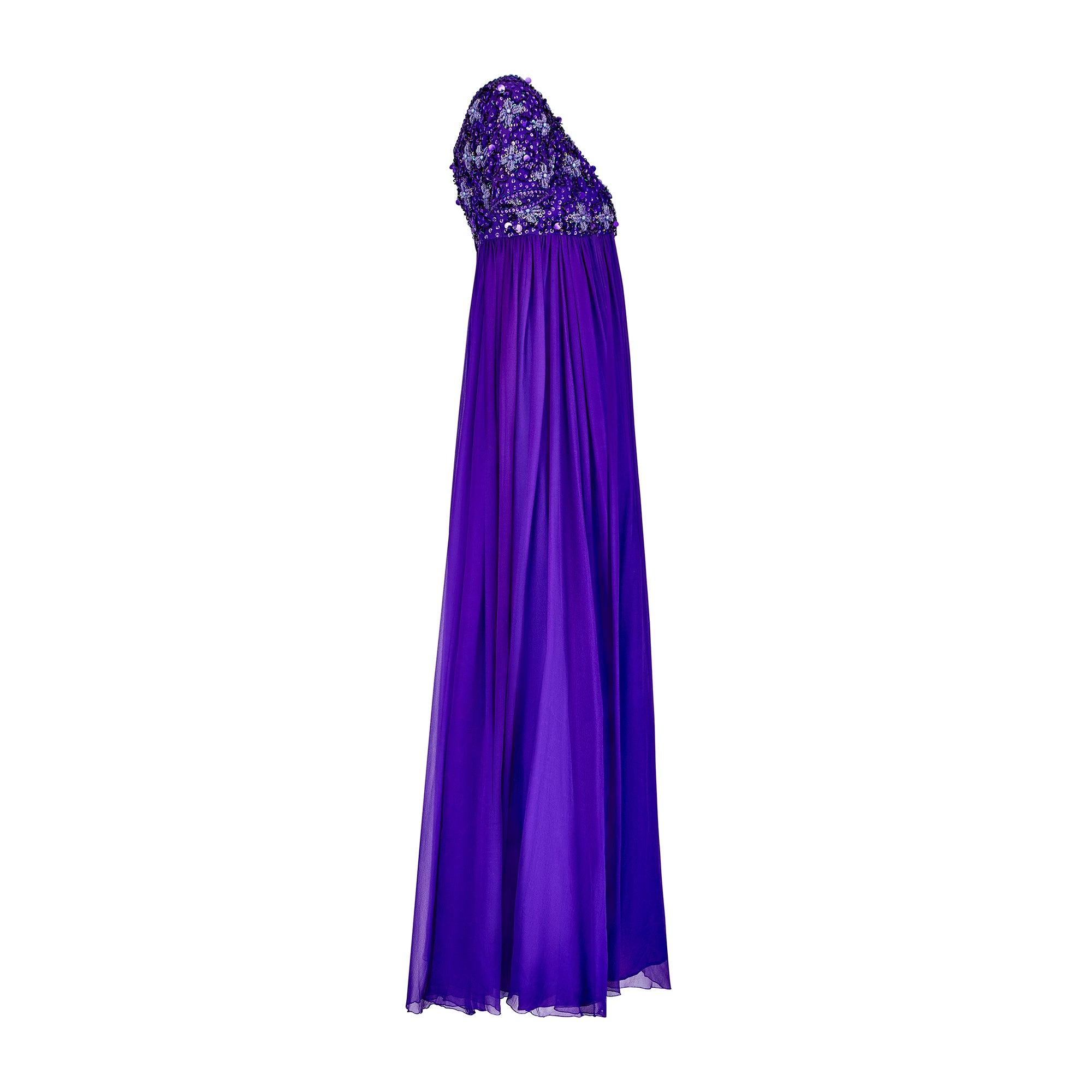 This 1960s couture amethyst purple dress is a real showstopper. Tailored from two frothy layers of purple silk of the finest quality, the top layer is made of soft flowing chiffon and the bottom is silk satin in a darker, deeper purple tone. The