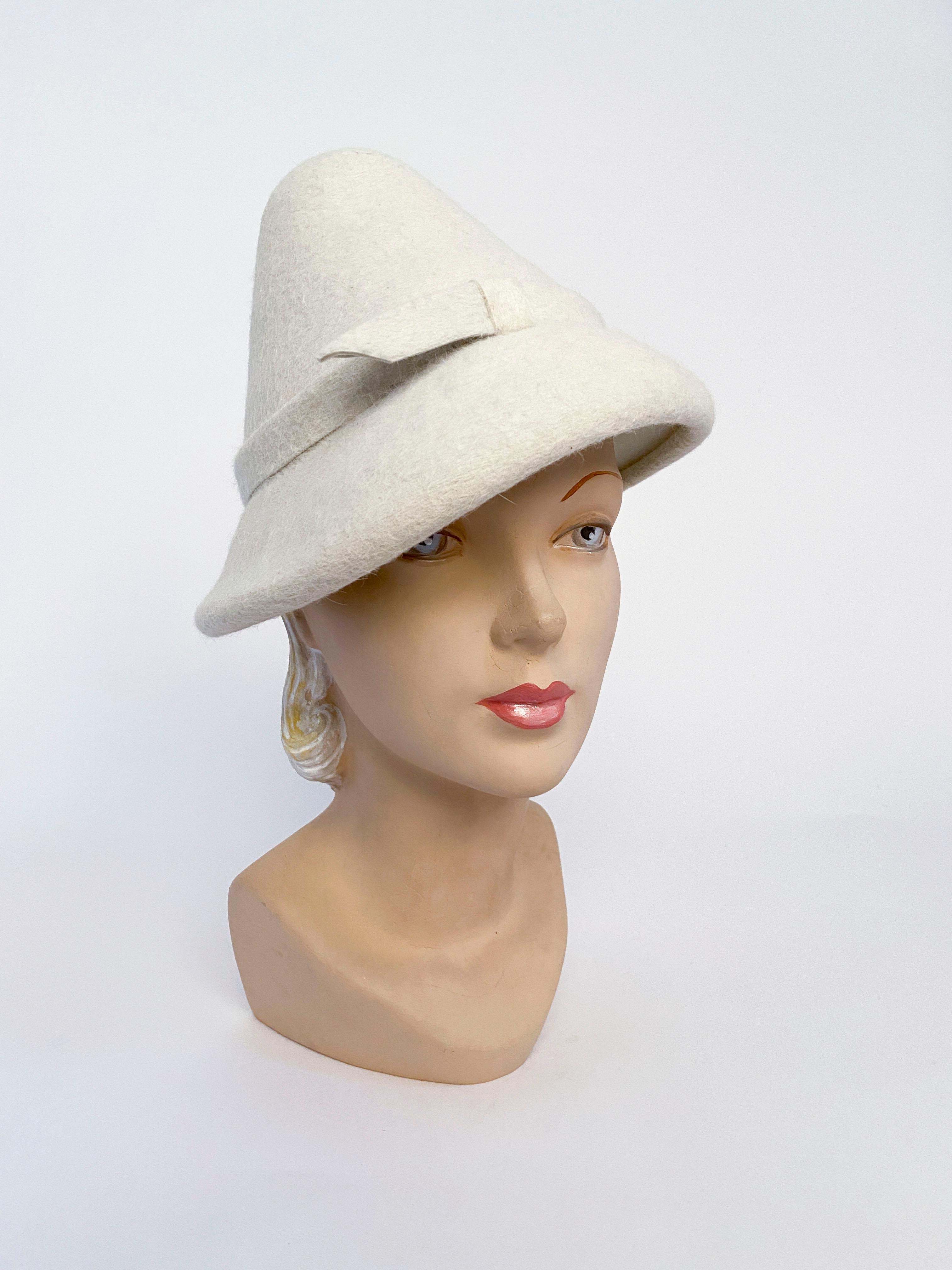 1960's cream fur felt hat hand sculpted into a high triangular crown finished with a thin hatband and decorative loop. Considering the age this hat was part of high fashion during the 1960s seen in fashion magazines.
