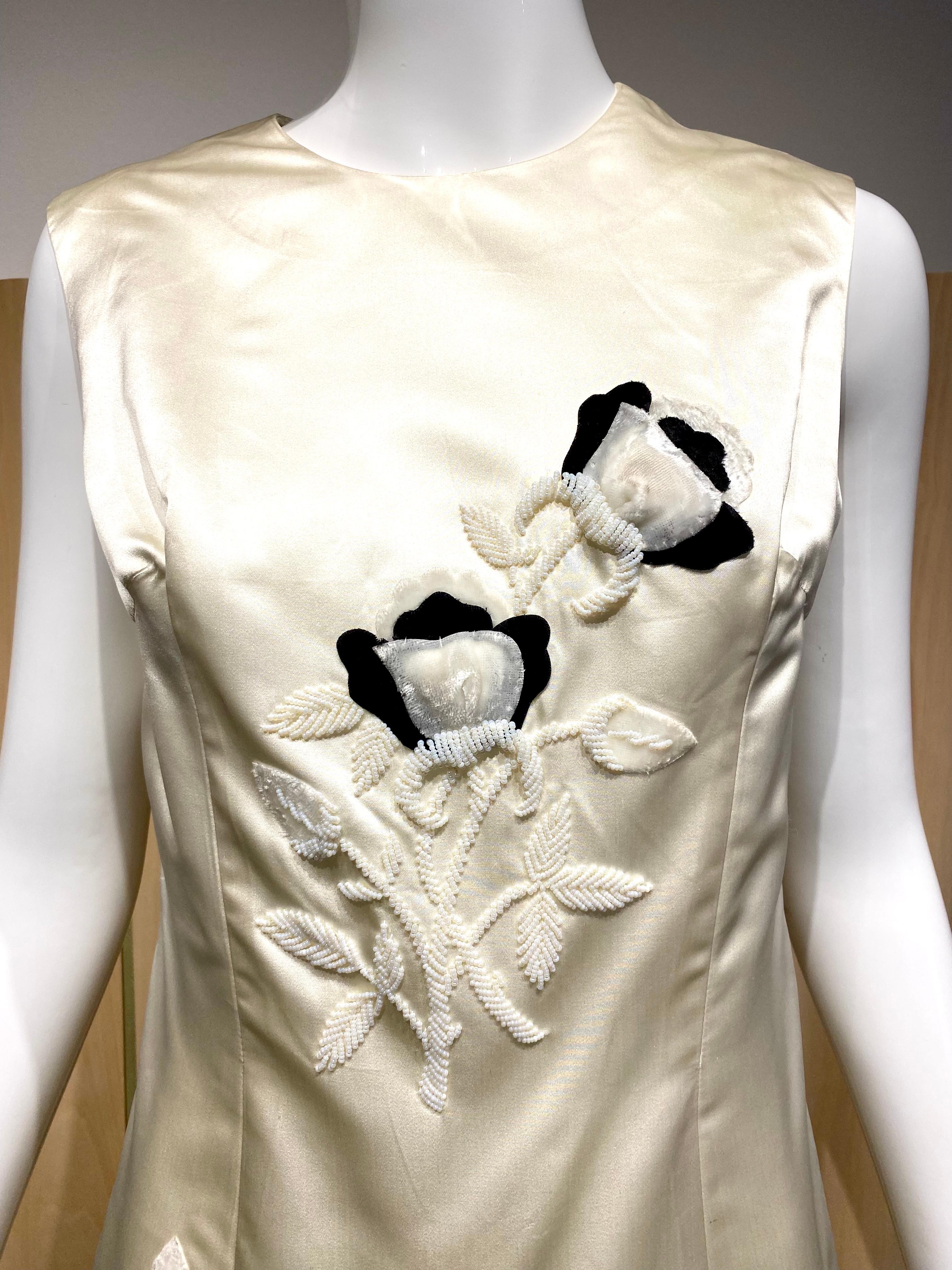 1960er Jahre Jackie O Creme Duchesse Satin Seide ärmelloses Kleid bestickt mit schwarzem Samt Blumenapplikationen und Perlen mit weißen Bügelperlen.
Perfekt für Sommer-Cocktailpartys.
Größe 6-8

Büste 36