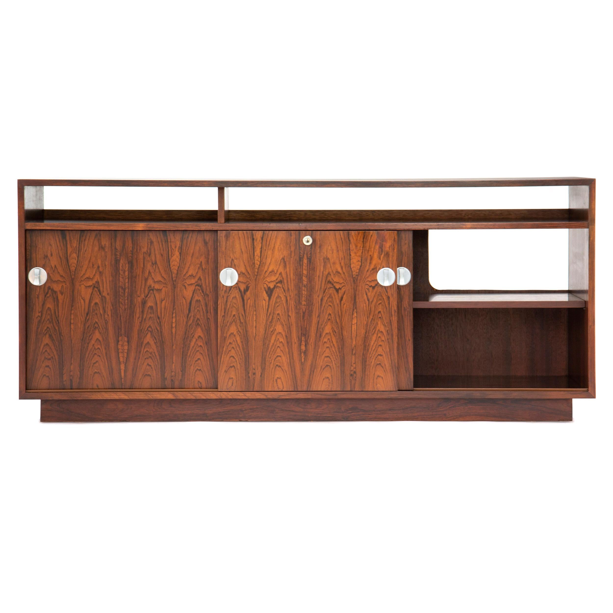 A credenza on a plinth base with a divided, open top shelf and having three sliding doors with aluminum bow-tie hardware. Part of the 'Cresco' modular wall unit. Can be combined with other 'Cresco' pieces.
