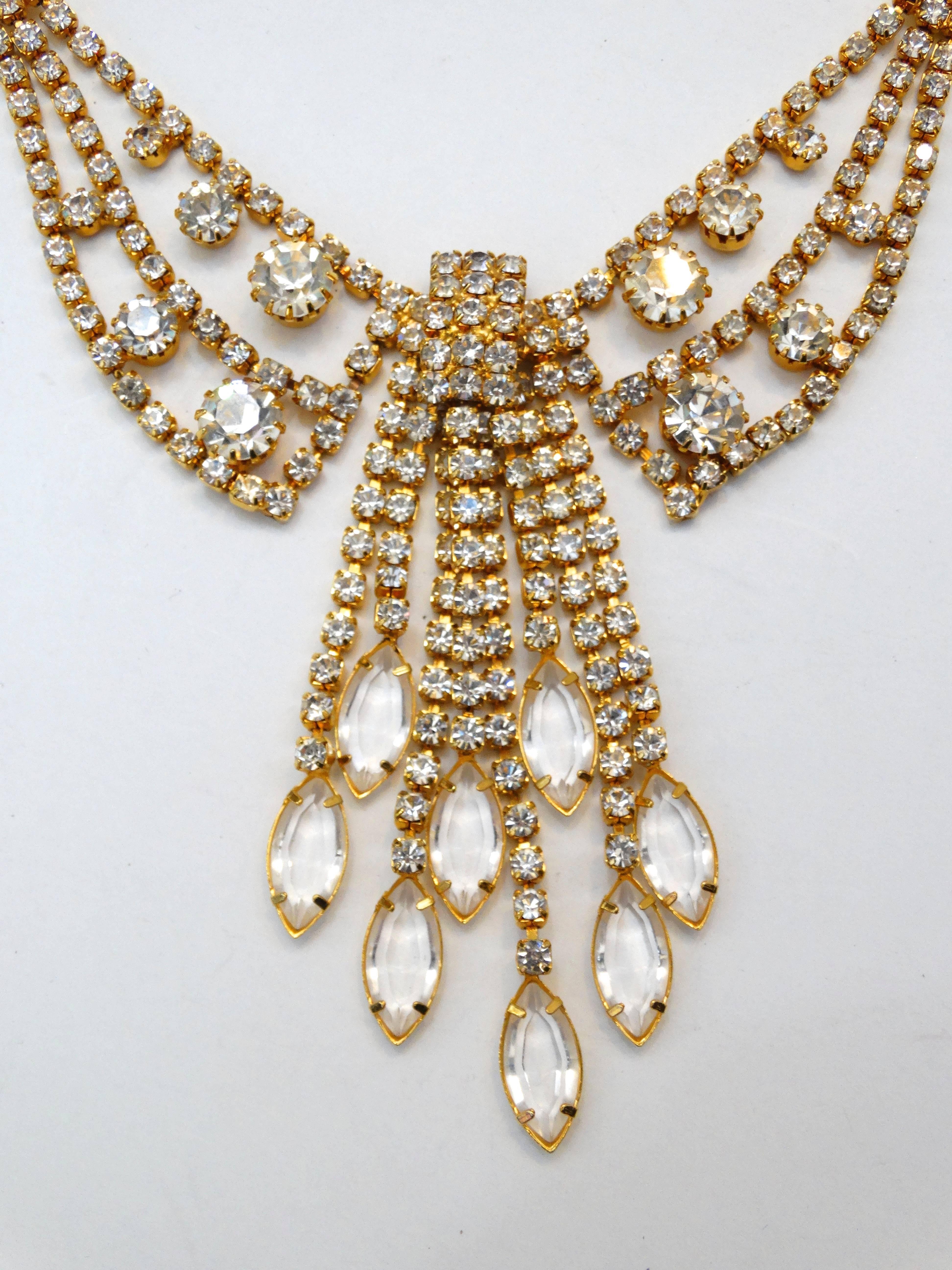 Accessorize with some sparkle with this incredible 1960s rhinestone bib necklace! Rows of brilliantly cut rhinestones set in gold toned metal. Accented with various sizes of rhinestones throughout. Collar style necklace with a strands of rhinestones