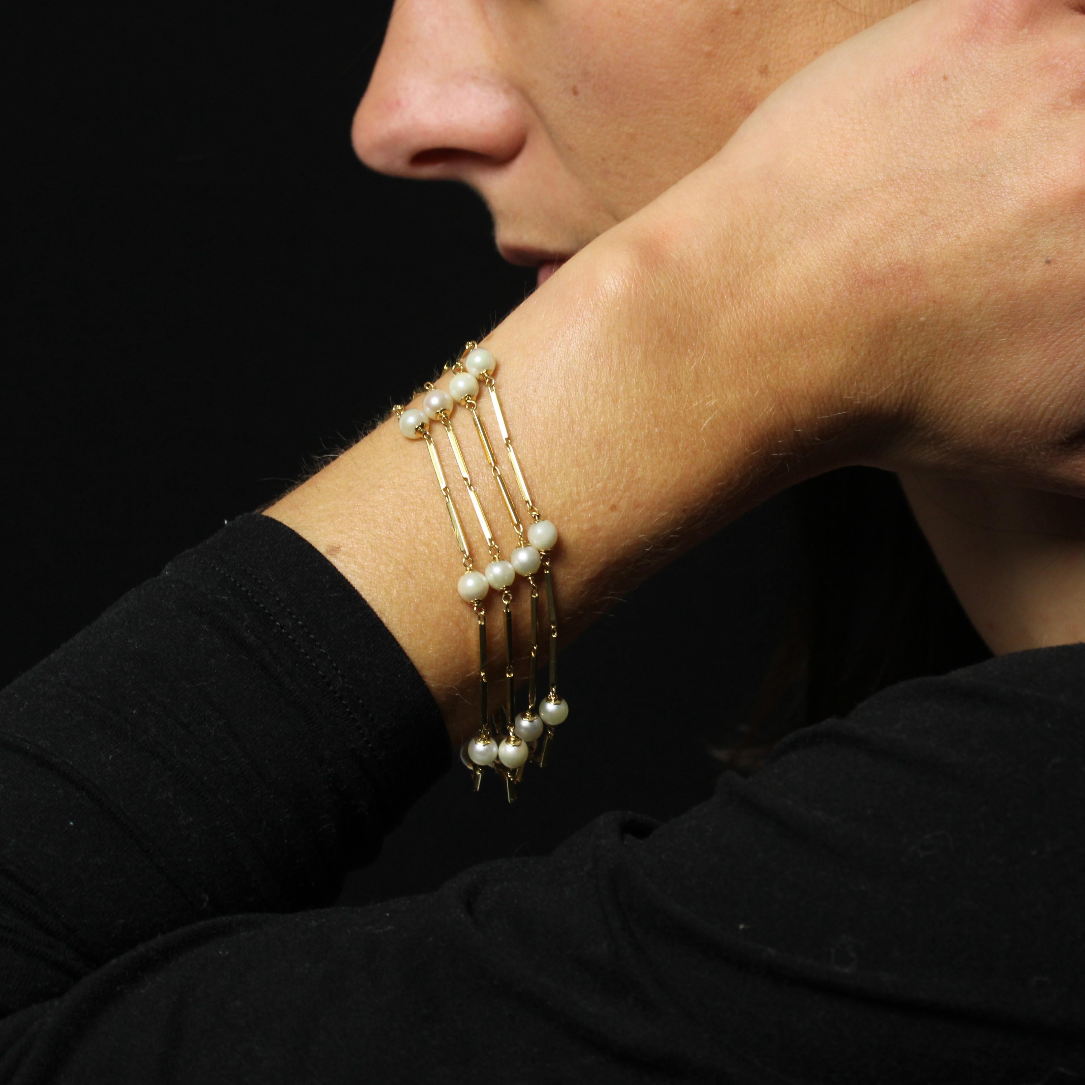 Bracelet in 18 karat yellow gold. 
Elegant vintage bracelet featuring 4 rows of small rectangular gold motifs hinged together, each spaced with 5 round pearly white cultured pearls. The clasp is ratchet with 8 safety pins.
Diameter of the pearls :