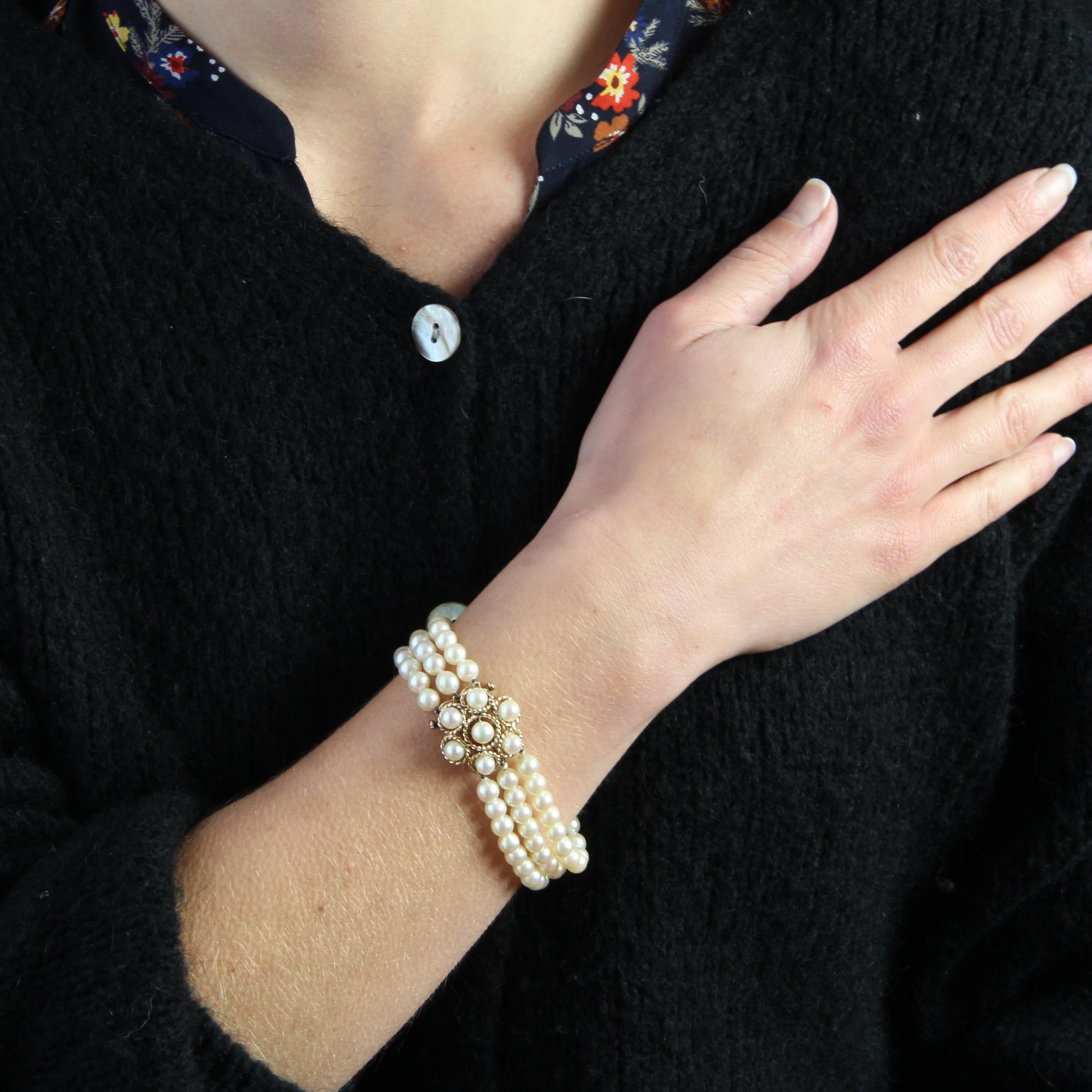 Armband, bestehend aus 3 Reihen weißer Orient-Zuchtperlen, der Verschluss ist ein blumenförmiges Muster aus Goldschnur und mit 7 Perlen verziert, die zu denen des Armbands passen. Die Schließe ist mit einer Ratsche versehen.
Durchmesser der Perlen: