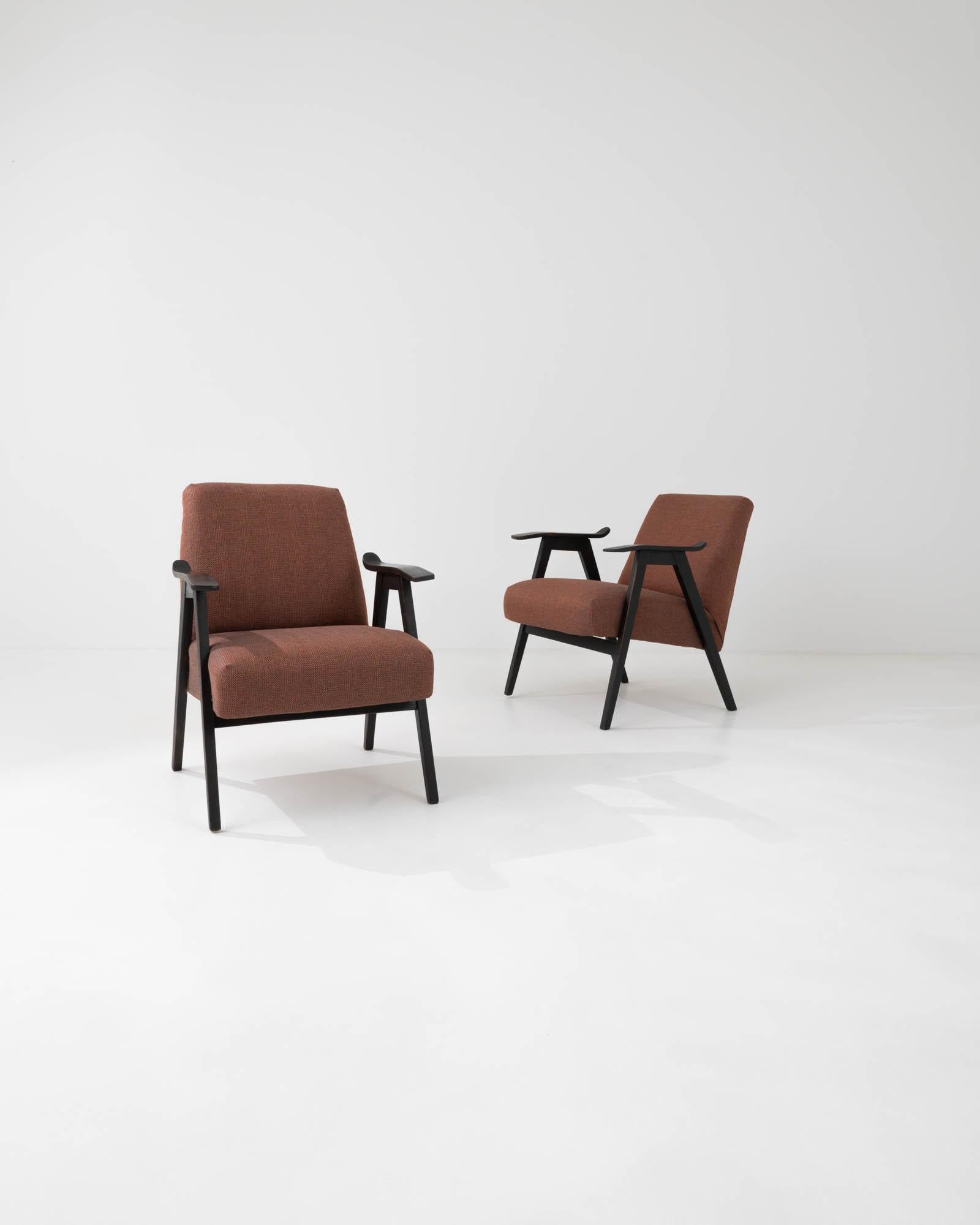 Caractérisés par les lignes épurées qui définissent leur silhouette minimaliste, ces fauteuils ont été fabriqués par l'emblématique entreprise de mobilier tchèque dans les années 1960. La courbe subtile et l'inclinaison douce des accoudoirs en bois