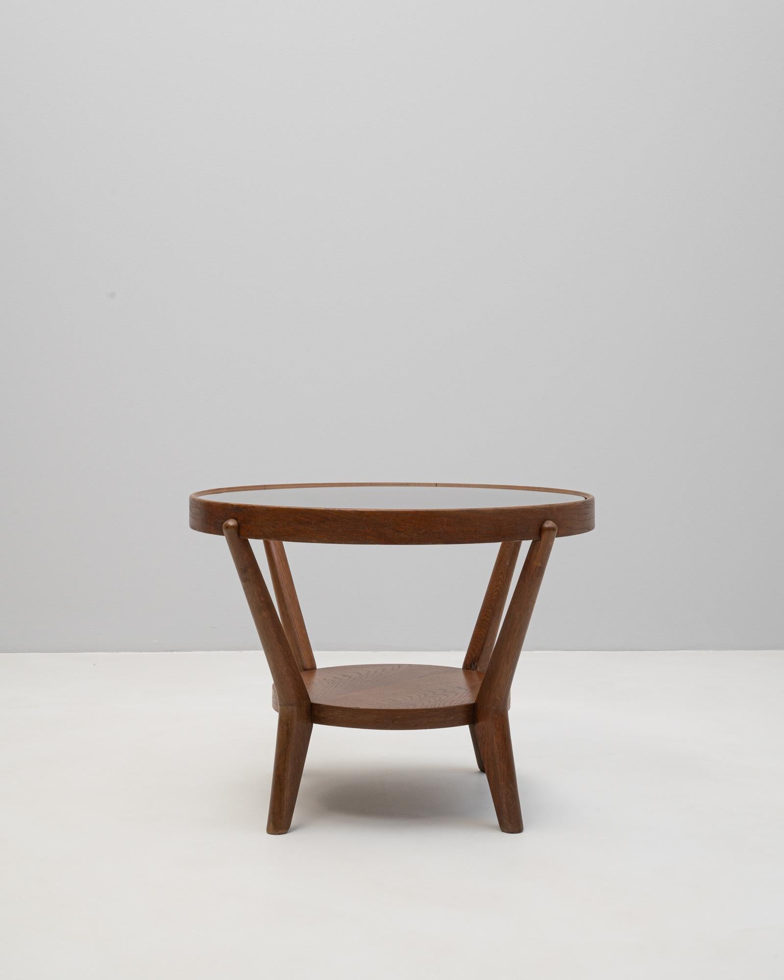 This 1960s Czech Art Deco coffee table by renowned designers Karel Kozelka and Antonín Kropáček is a refined example of mid-century craftsmanship. The circular top, made of glass, is supported by three angled legs that connect to a solid lower