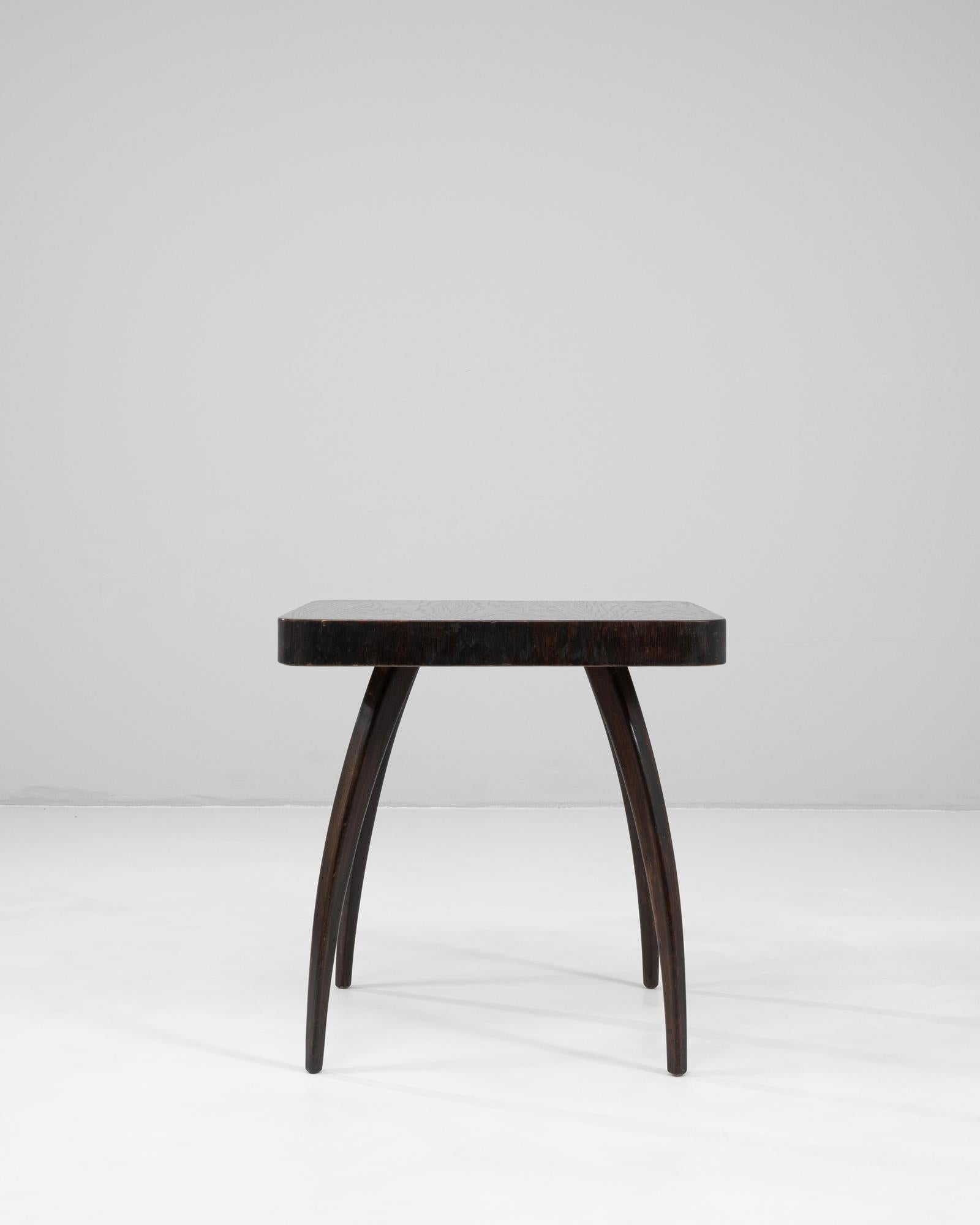 This 1960s Czech spider table by Jindřich Halabala showcases the designer’s mastery of sculptural form and mid-century innovation. Crafted in wood with a deep black patinated finish, the table’s distinctive curved legs radiate outward from the