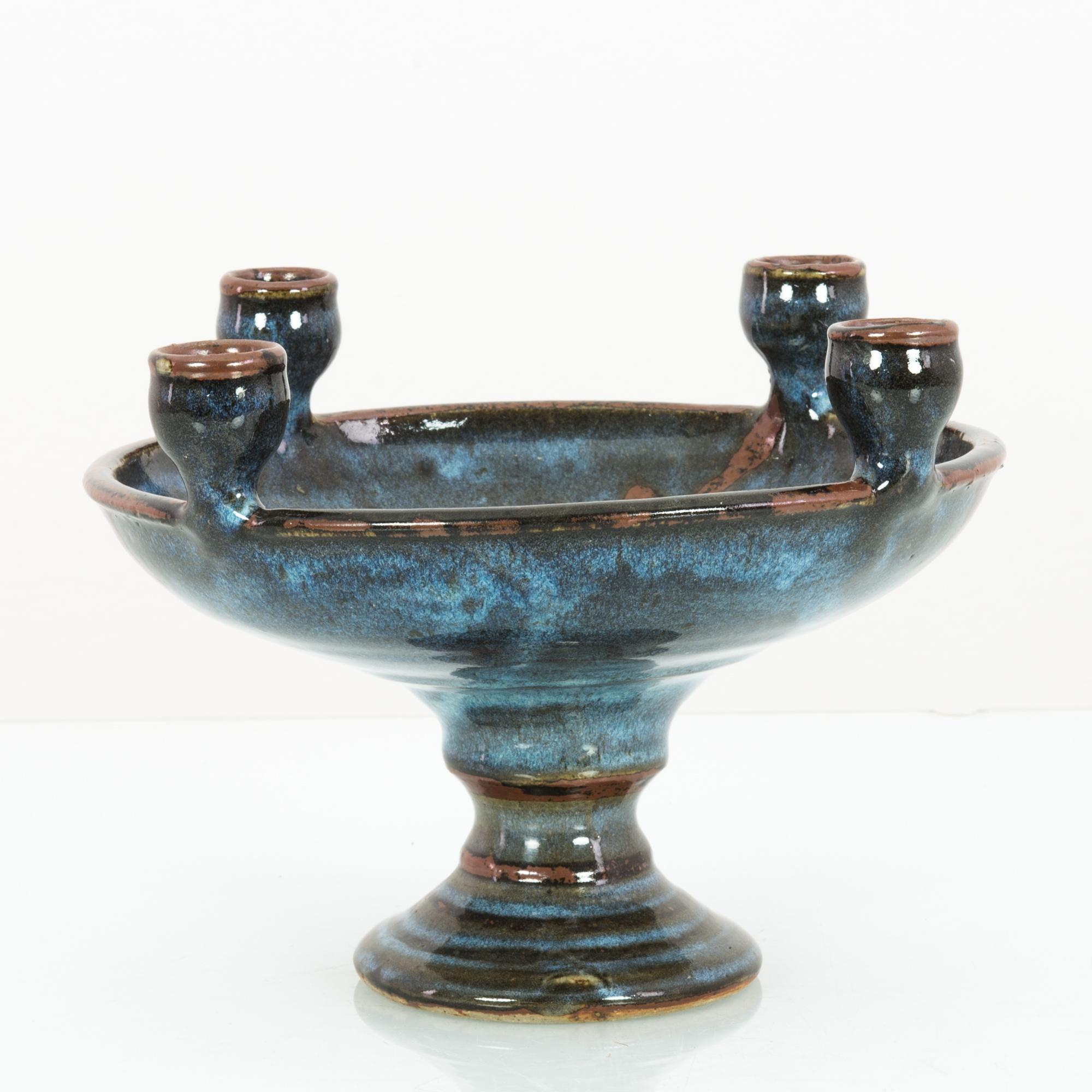 A ceramic candlestick from Czechia, circa 1960. Four candleholders sit upon the rim of a broad dish, glazed in black and indigo, giving the ceramic the aspect of a moonlit sky. The rim of the candleholders and bowl are bordered in brown ochre,