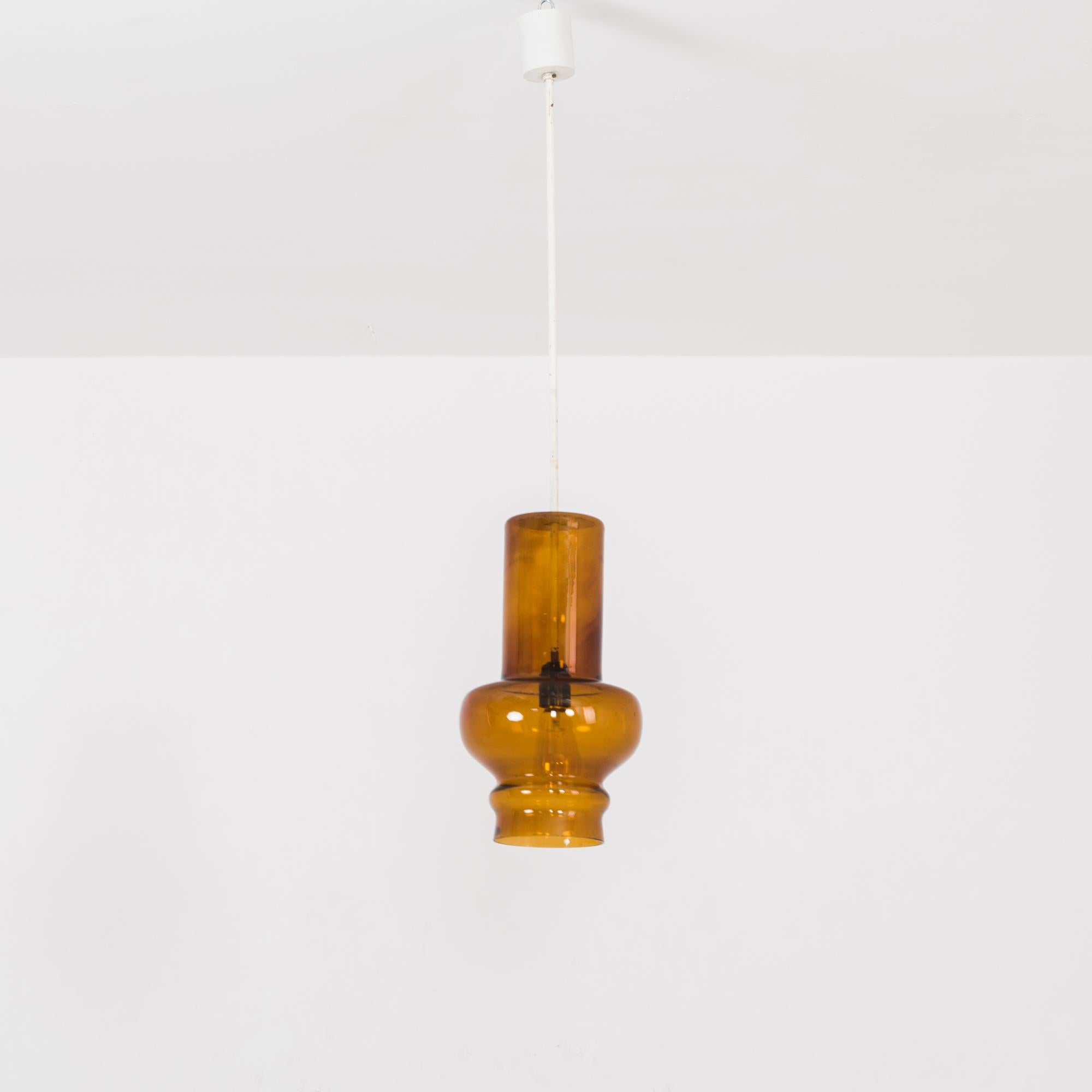 This pendant lamp was made in the former Czechoslovakia, circa 1960. It features a patinated white metal rod attached to a glass cloche. The cylindrical upper half of the cloche widens to a rounded body near the bottom. With its soothing shade of