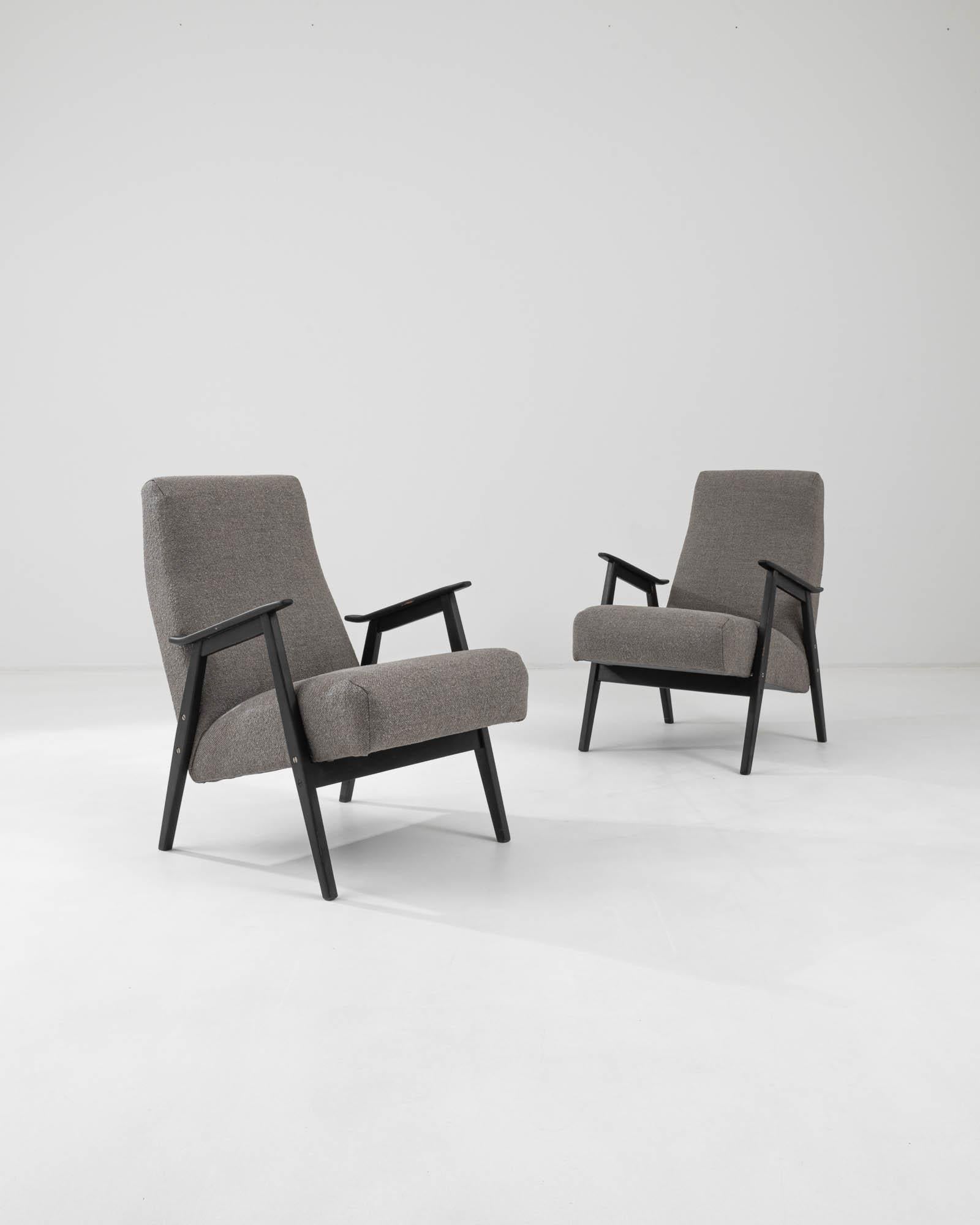 This pair of 1960s Czech armchairs provide the perfect nook in which to watch the world go by. The seat, generously cushioned and set at an inviting recline, seems to float like a cloud between the branches of the angular wooden frame. The grey