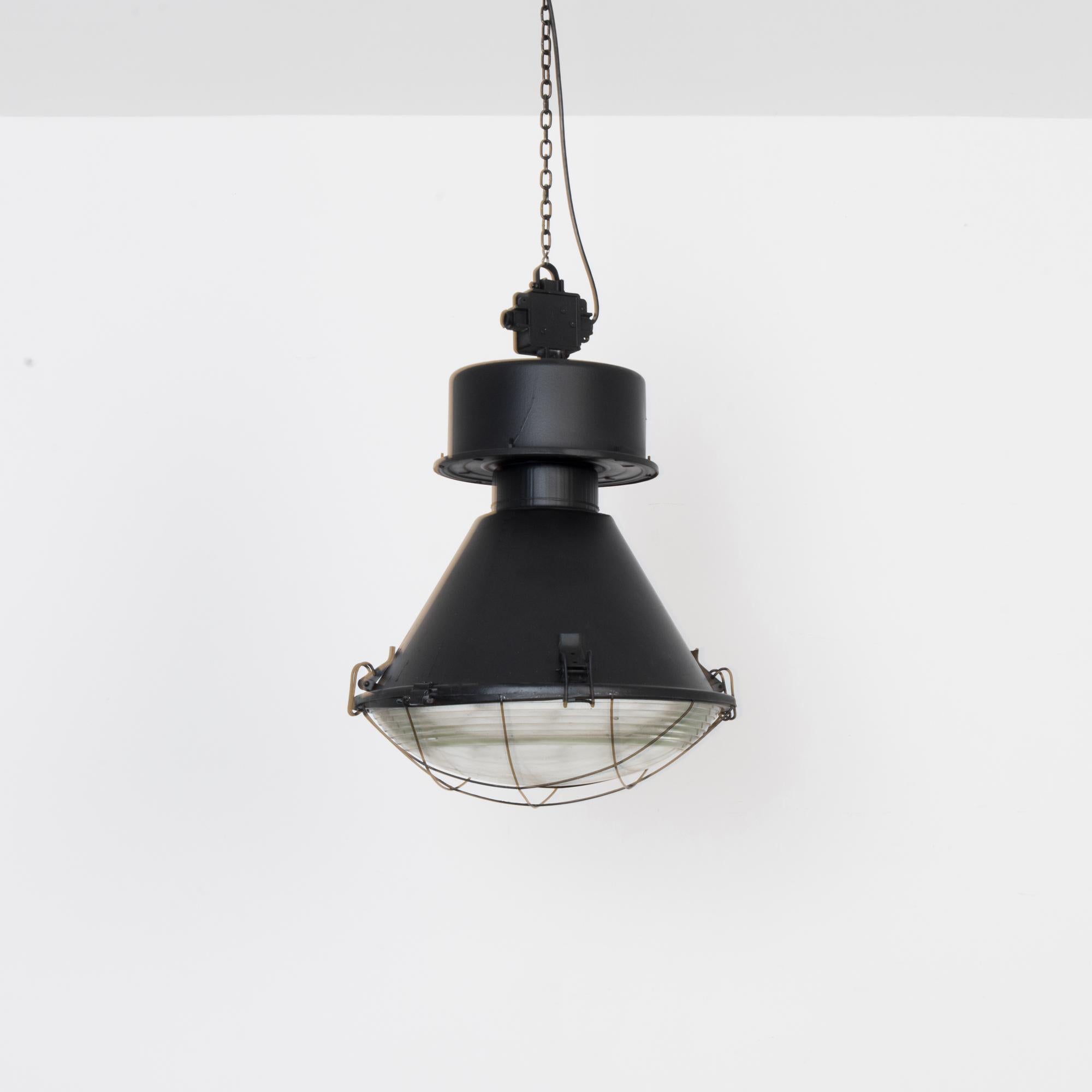 Original finishes and hardware, re-electrified and fitted for E26 socket. Enclosed in thick textured glass, this large scale industrial pendant blends clean lines with bold geometric forms. A sturdy and stylish industrial touch in your space.