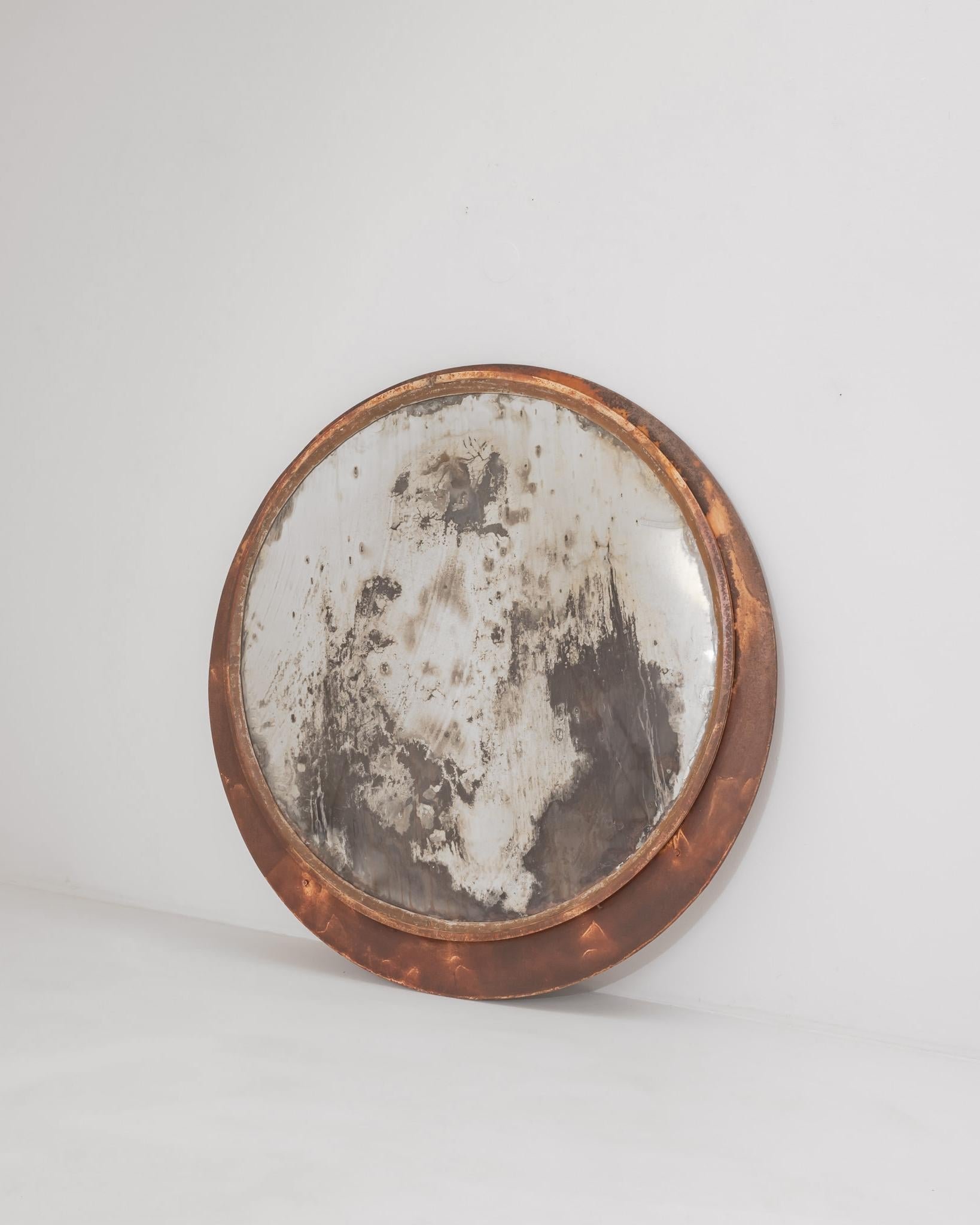 The dramatic patina of this vintage metal mirror lends it a sculptural presence. Made in Czechia in the 1960s, the mirrored disk is set asymmetrically within a circle of painted metal. The silver surface has tarnished to reveal the dark charcoal