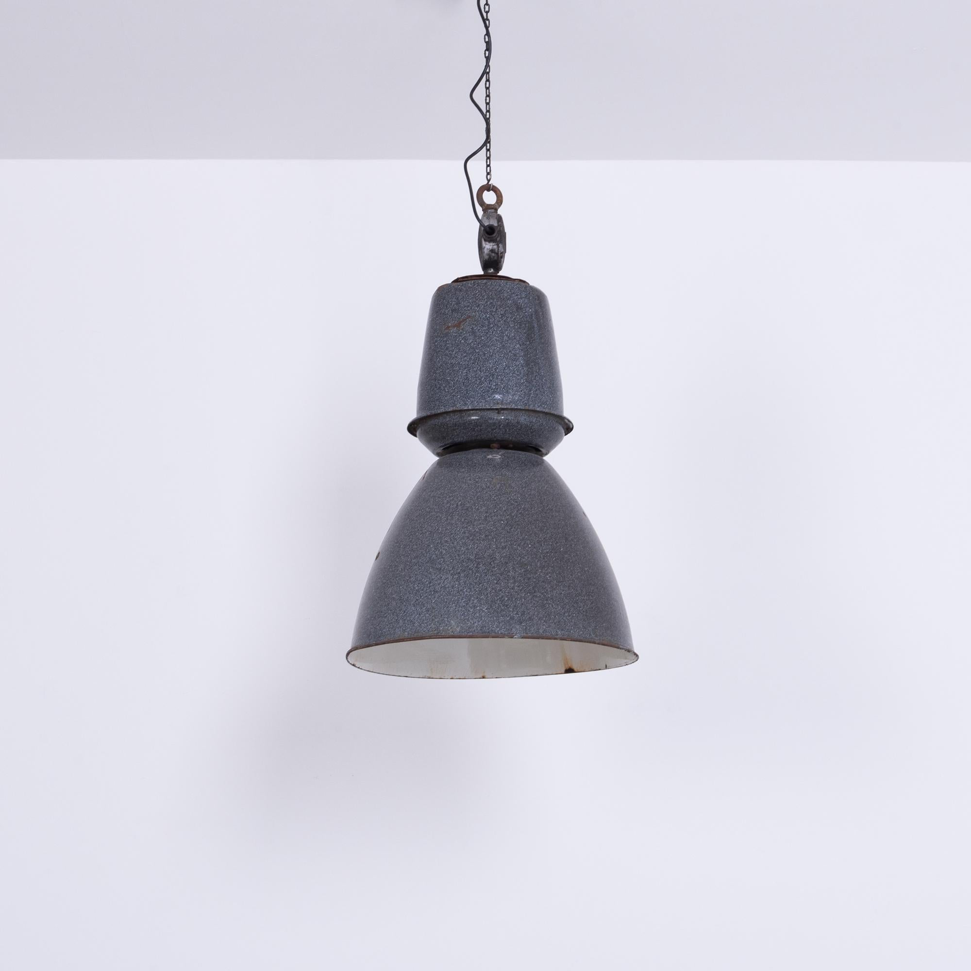 Questa lampada a sospensione in metallo, che trasmette l'essenza del fascino industriale, è un esempio straordinario di design funzionale trasformato in arte. Risalente alla metà del XX secolo, la sua forma robusta era senza dubbio destinata a una