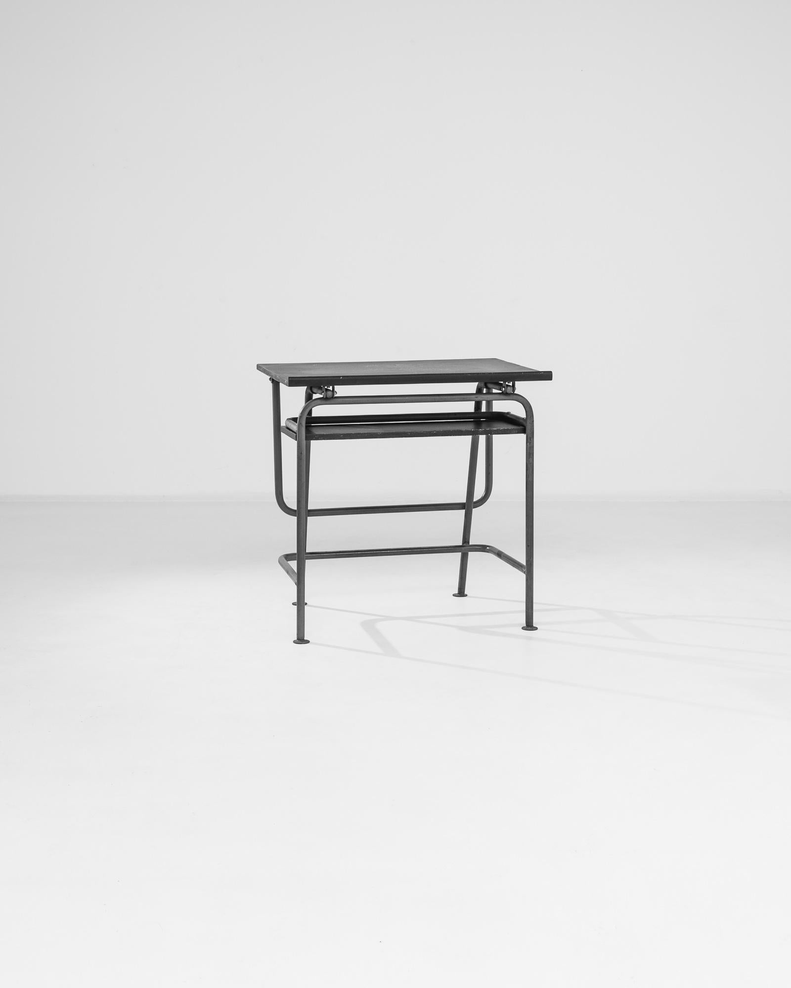 Transport yourself back to the charming classrooms of the 1960s with this vintage Czech metal school desk, a nostalgic piece that exudes simplicity and functionality. Crafted from sturdy black metal with various supporting bars, this desk stands the