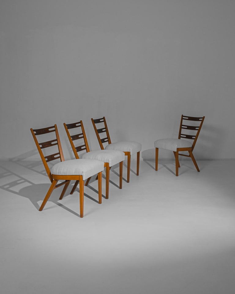 A set of four wooden dining chairs from 1960s Czechia. A Modernist design with an immediate visual impact. The angular tilt of the back leg and the decorative apertures of the backrest create eye-catching graphic accents, and does the dual tone of