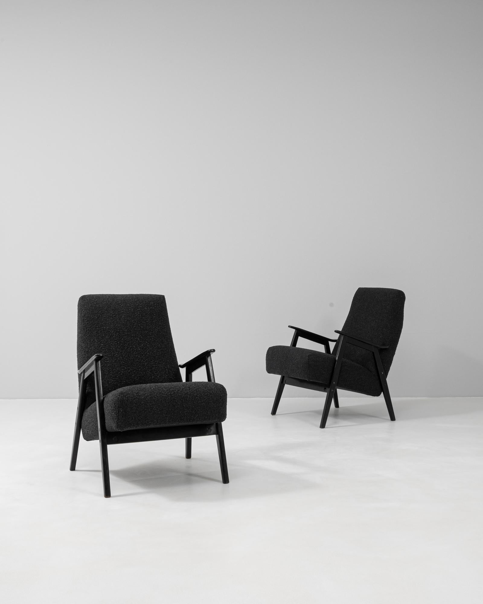 Esta pareja checa de sillones tapizados de los años sesenta refleja las líneas limpias y la refinada practicidad del diseño moderno de mediados de siglo. Cada silla tiene un elegante armazón de madera negra con reposabrazos angulosos y patas