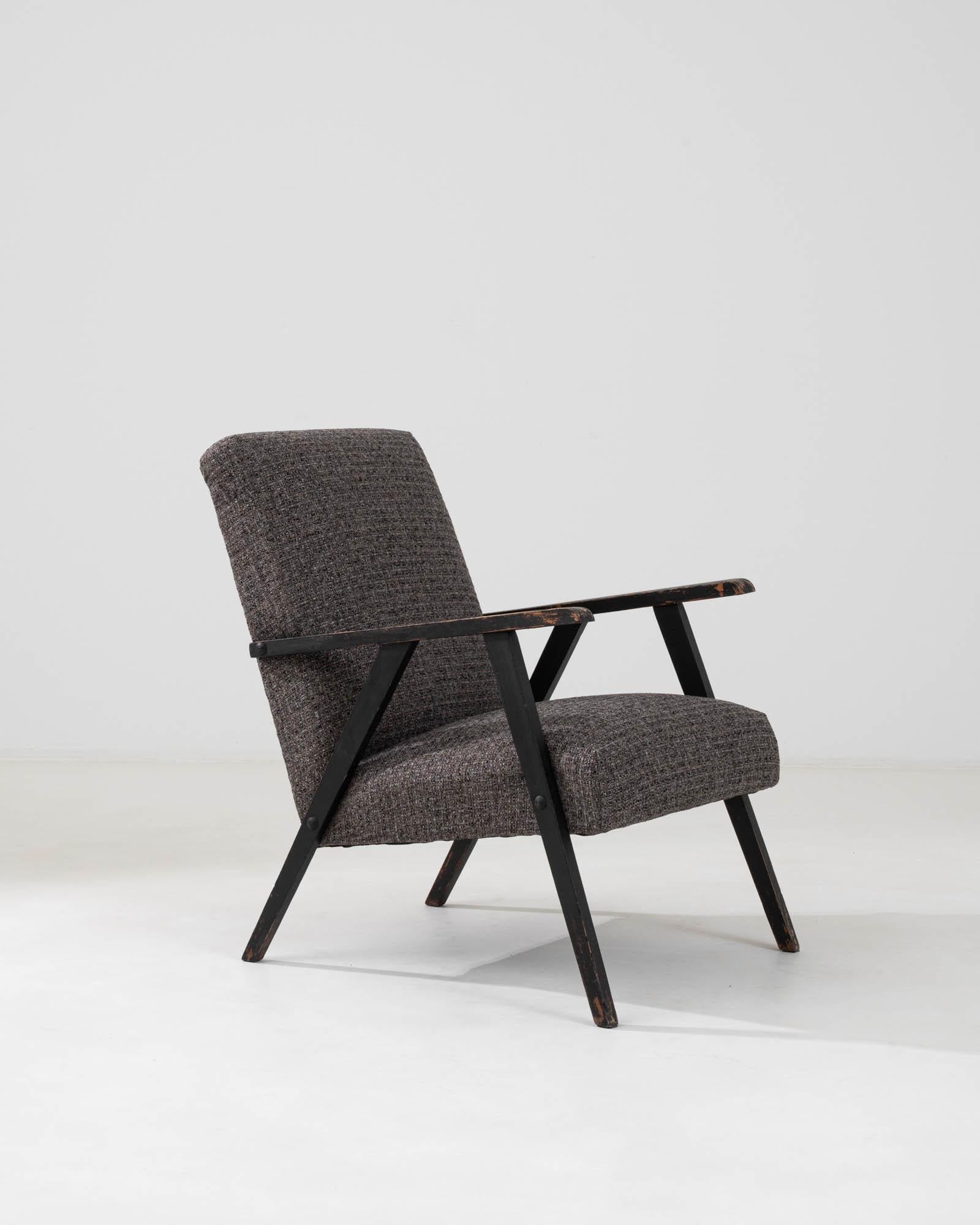 This 1960s Czech Upholstered Armchair encapsulates the essence of vintage appeal with its textured upholstery in muted earth tones. The chair's strikingly simple and functional design, with its clean lines and sleek black frame, nods to the era's