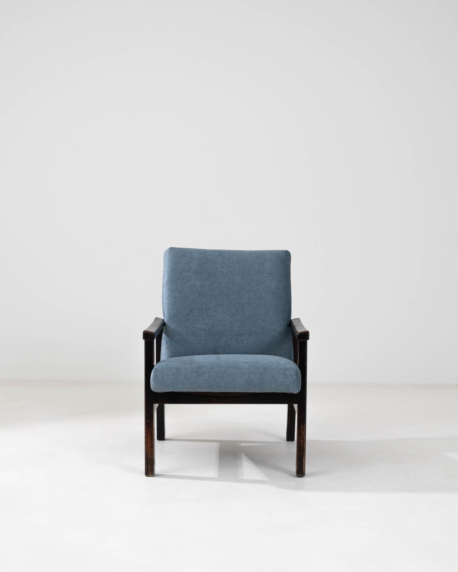 Introducing the essence of 1960s charm with this Czech upholstered armchair, a testament to timeless design and comfort. The chair's body is swathed in a serene, ocean-blue upholstery that whispers both calm and sophistication. Its wooden frame,
