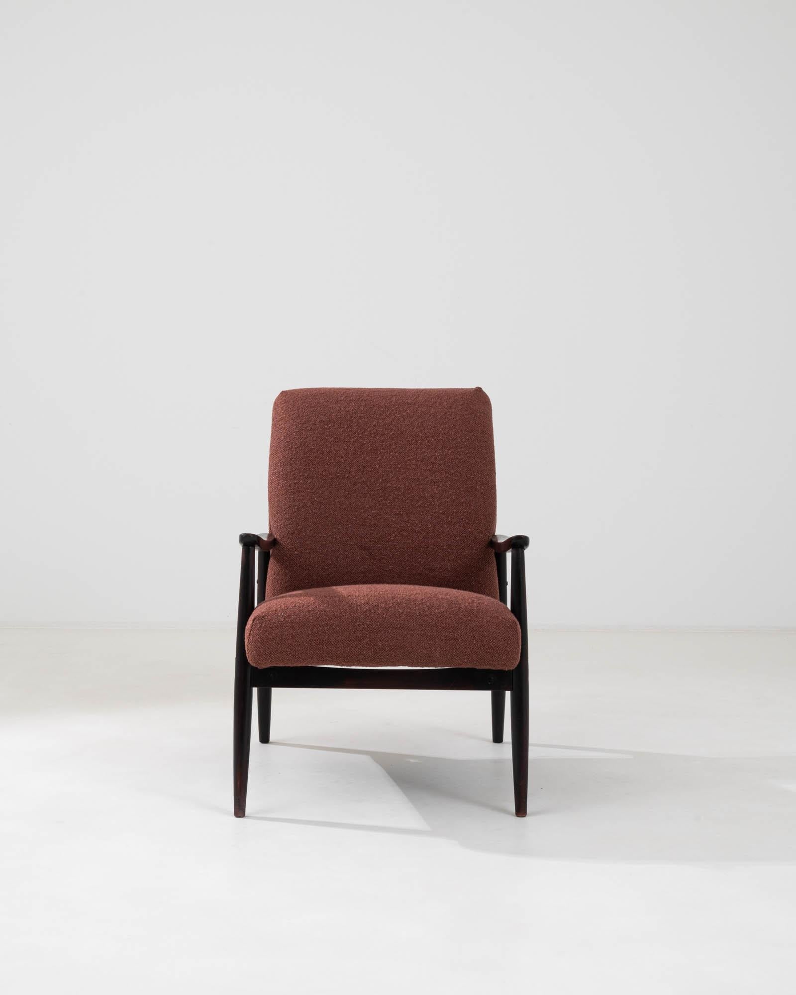 Step into the retro elegance of the 1960s with this Czech upholstered armchair. Dressed in a rich, textured rust fabric, it's a nod to the era's penchant for bold, confident colors and comfort. The armchair's design is grounded by a robust, dark