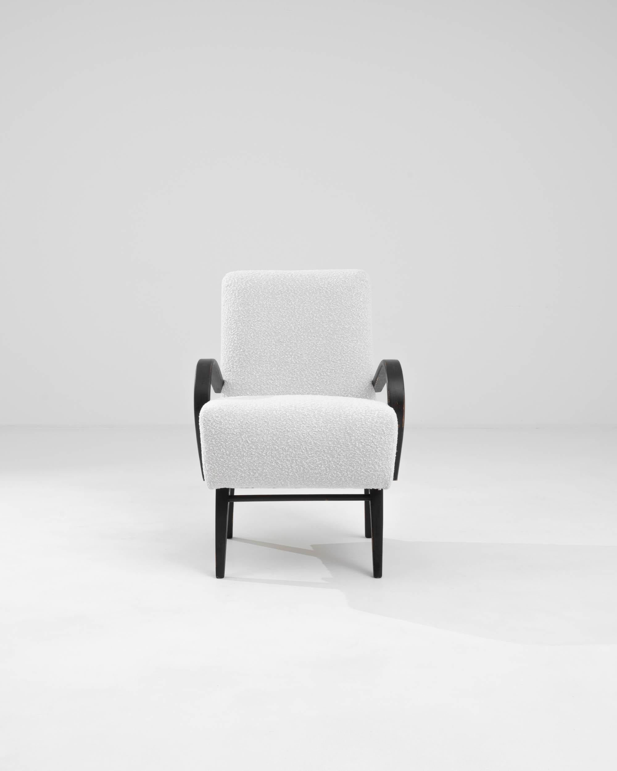 Elevate your home decor with this exquisite 1960s Czech Upholstered Armchair, a quintessential piece of mid-century modern design. Featuring a sturdy black wooden frame, this chair boasts a striking contrast with its plush white upholstery, creating