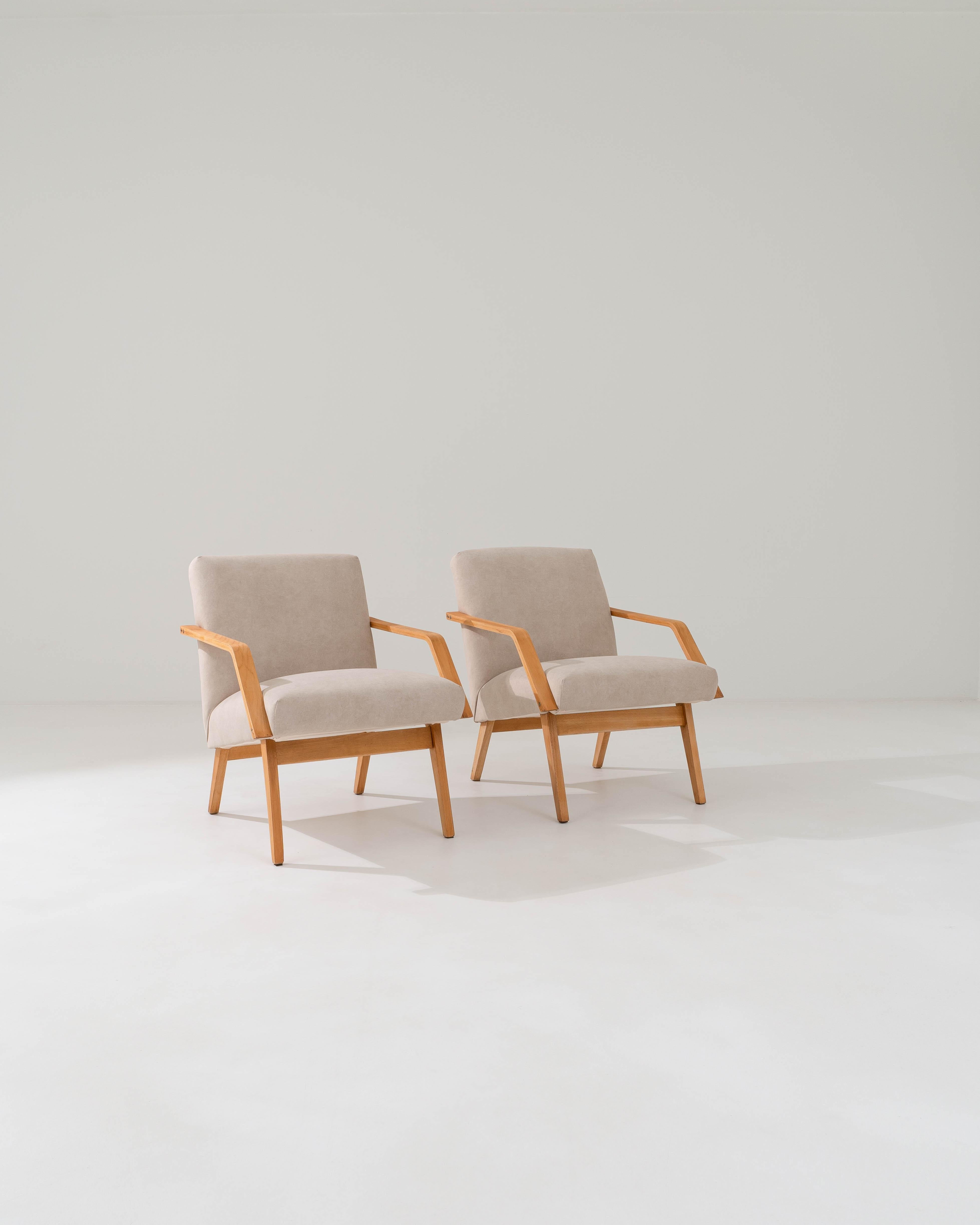 Légère et élégante, cette paire de fauteuils du milieu du siècle met en valeur la sophistication du design moderniste d'Europe centrale. Fabriqué en Tchécoslovaquie dans les années 1960, les angles nets des pieds fuselés et les accoudoirs élancés en