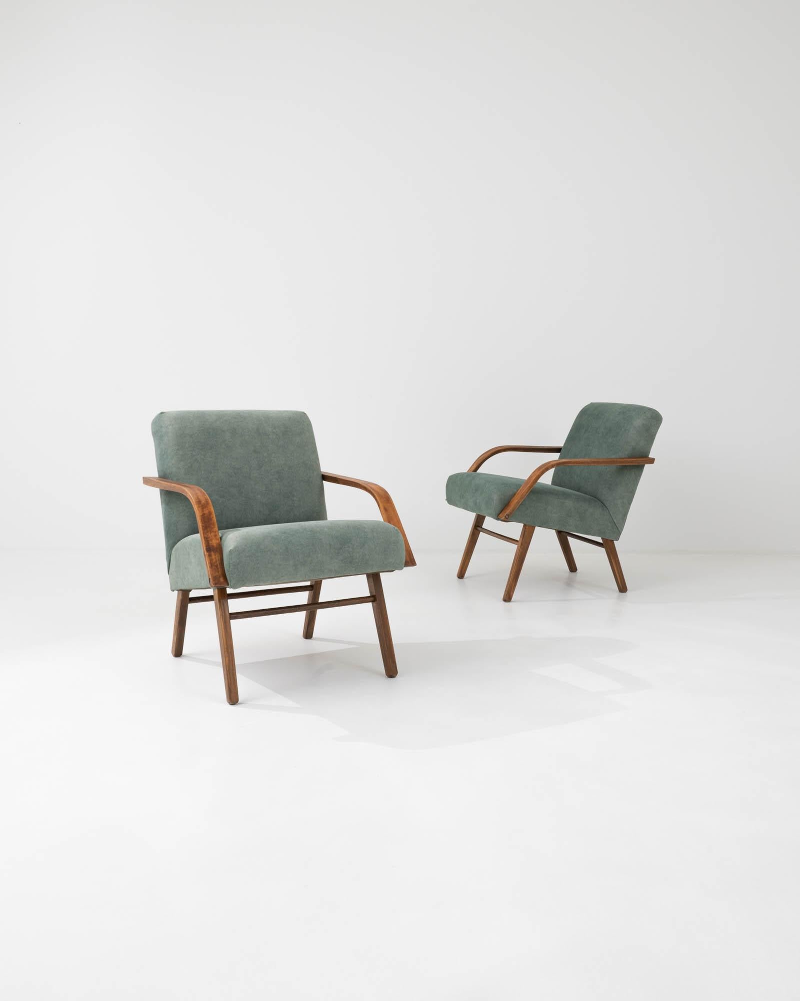 Light and stylish, this pair of Mid-Century armchairs showcase the sophistication of Central European Modernist design. Produced in the former Czechoslovakia, the clean angles of this 1960s design combines tapered legs and slender bentwood armrests