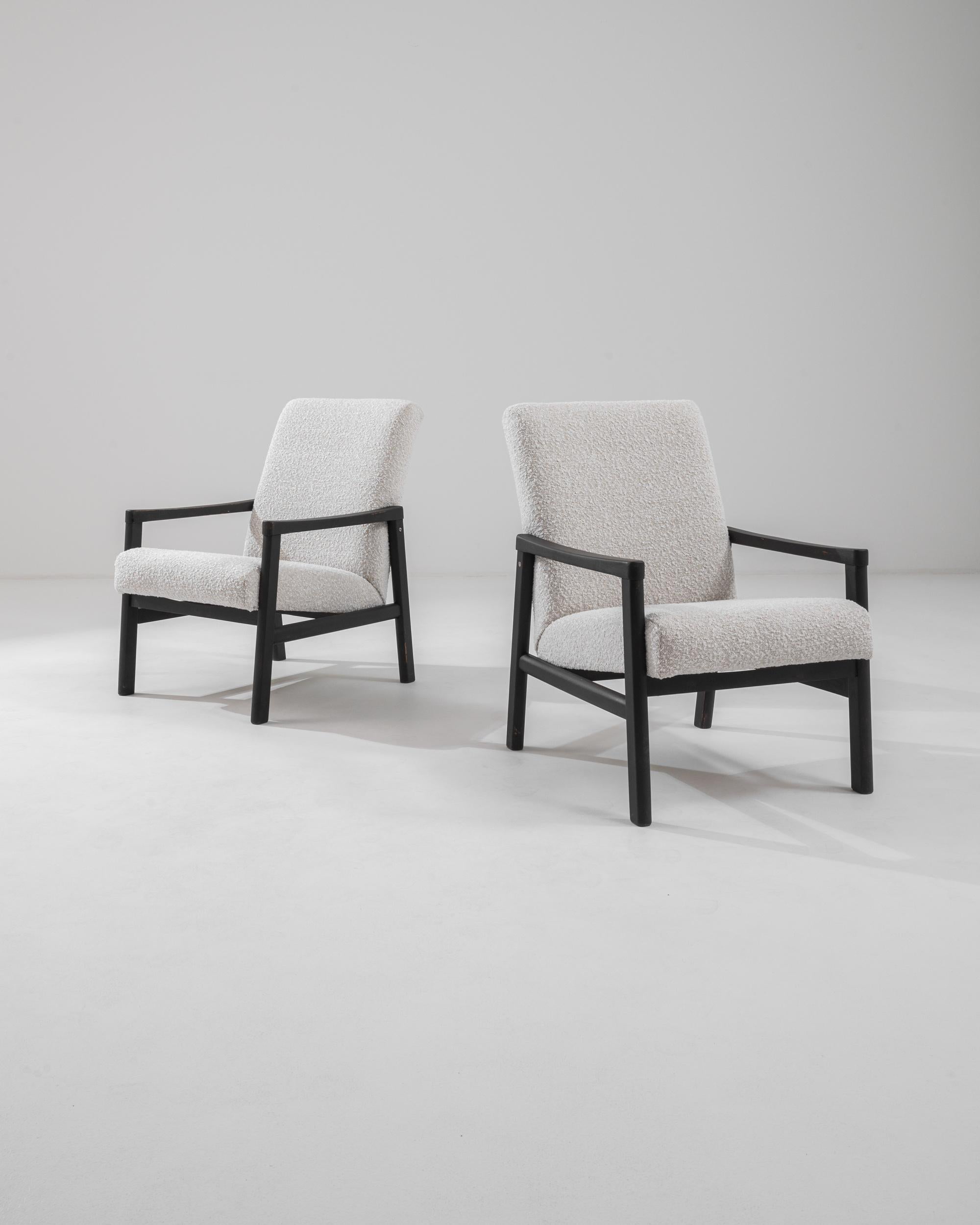 Immerse yourself in the retro allure of our 1960s Czech Pair of Upholstered Armchairs, a duo that beautifully embodies the spirit of mid-century design. These chairs feature a robust frame with sleek black lines that form a striking contrast against