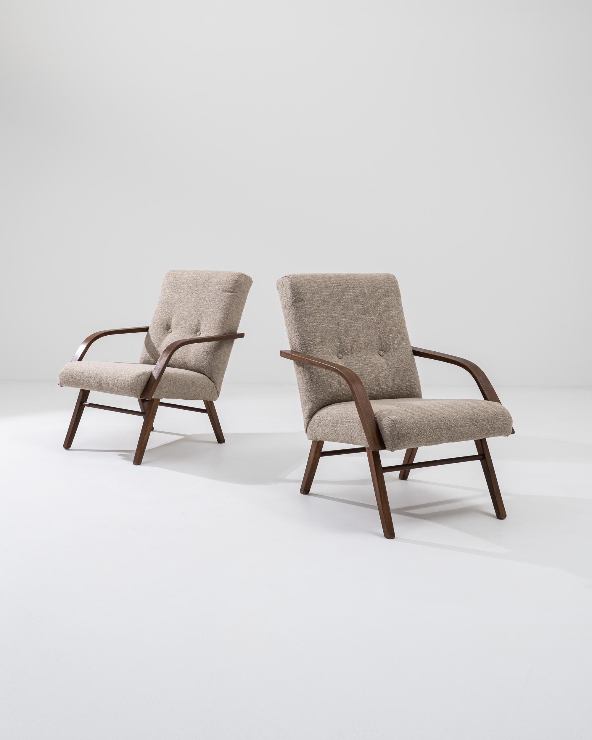 Eleva il tuo spazio abitativo con questa splendida coppia di poltrone imbottite ceche degli anni '60. Queste sedie mostrano l'elegante semplicità del design di metà secolo, con braccioli e gambe in legno curvato in una finitura ricca e calda. La