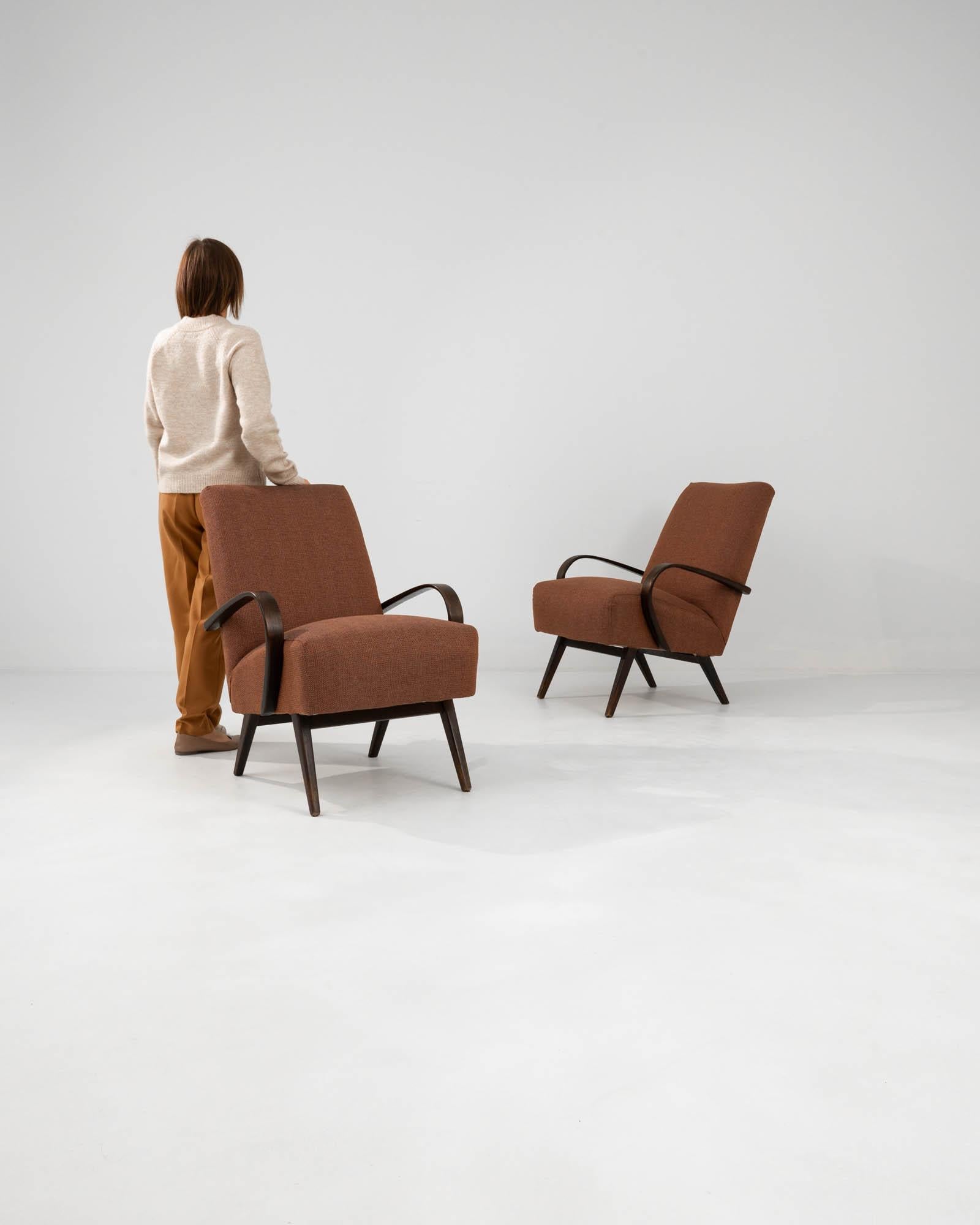 Infuse your living space with the timeless elegance and distinct design of these 1960s Czech upholstered armchairs by J. Halabala. Each chair exudes a warm, inviting aura with its rich terracotta-colored fabric, perfectly complementing the dark