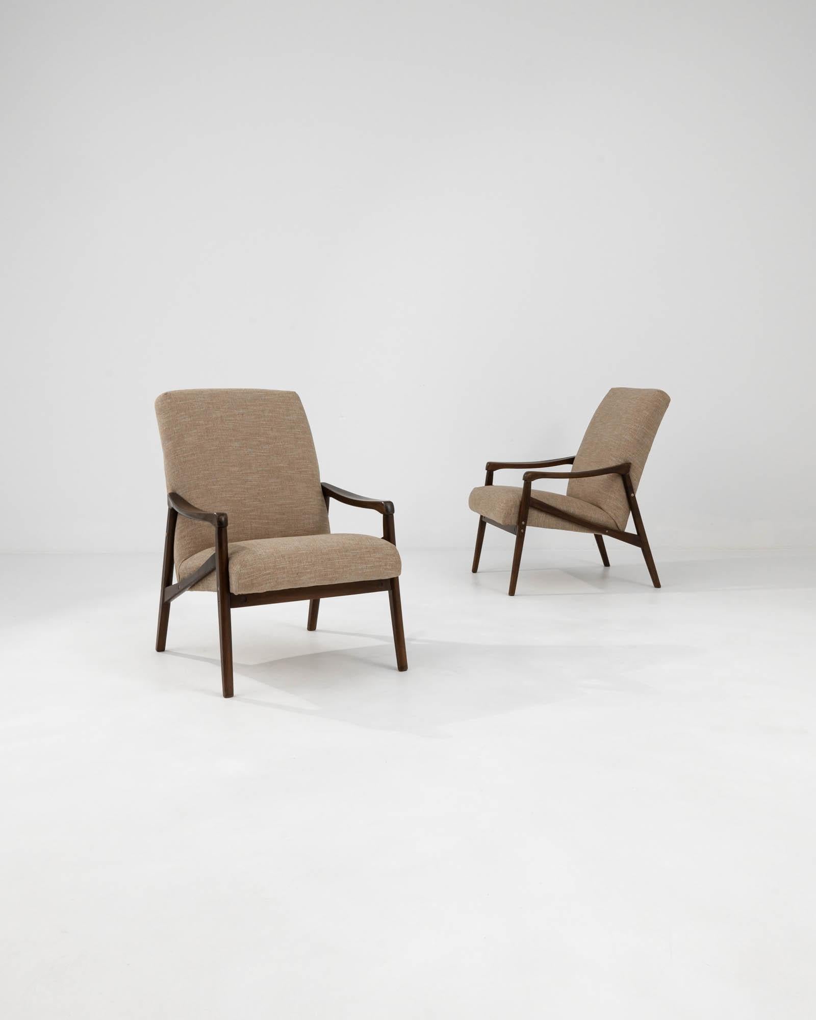 Voici les fauteuils tapissés tchèques des années 1960 de Jiri Jiroutek, une paire qui incarne l'esprit du design moderne du milieu du siècle avec un soupçon de charme de l'Europe de l'Est. Les lignes nettes et angulaires du cadre en bois foncé sont