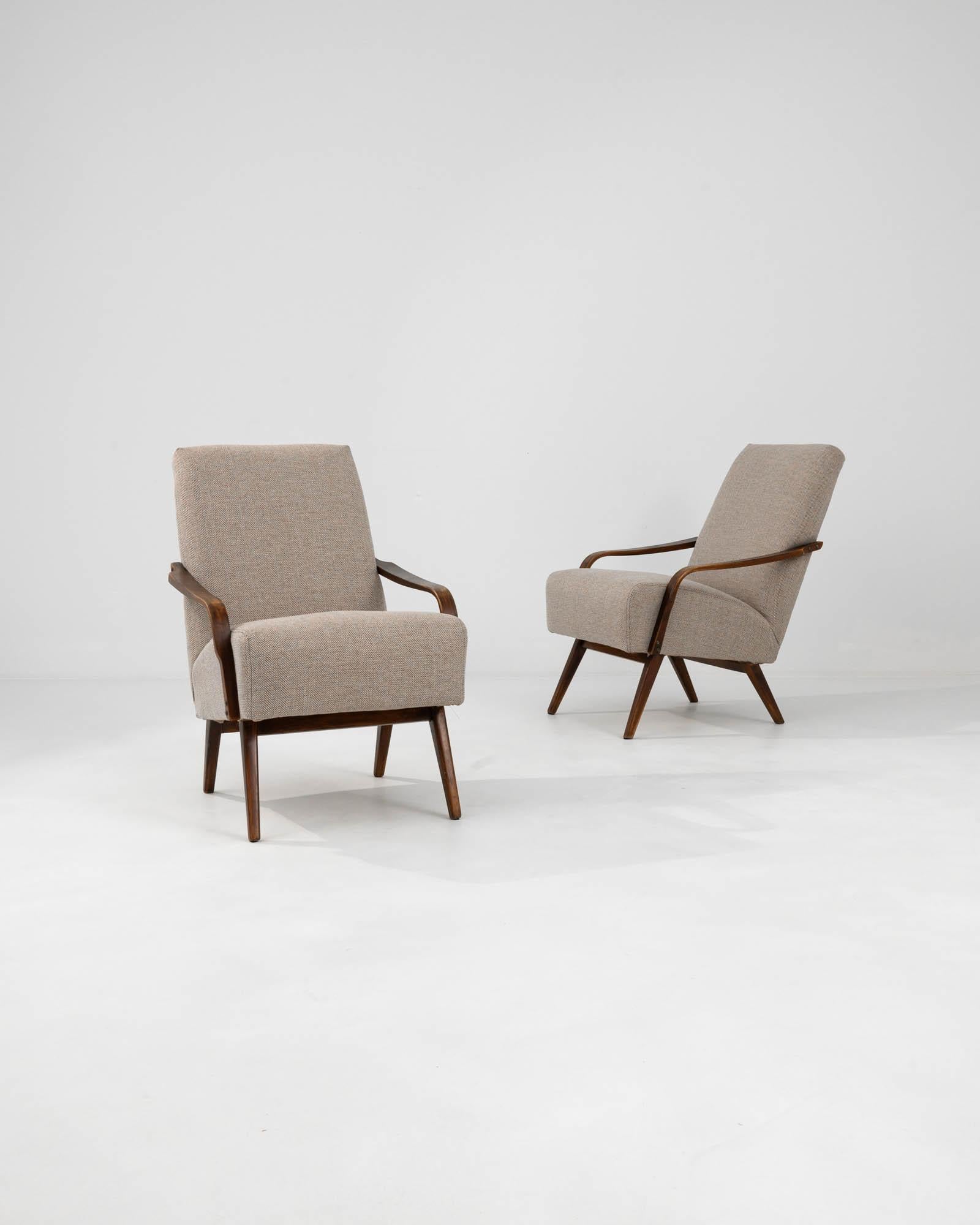 Introducing the 1960s Czech Upholstered Armchairs by TON, a pair that encapsulates the spirit of mid-century modern design with a hint of Eastern European charm. The clean, angular lines of the dark wooden frame are a nod to the minimalist