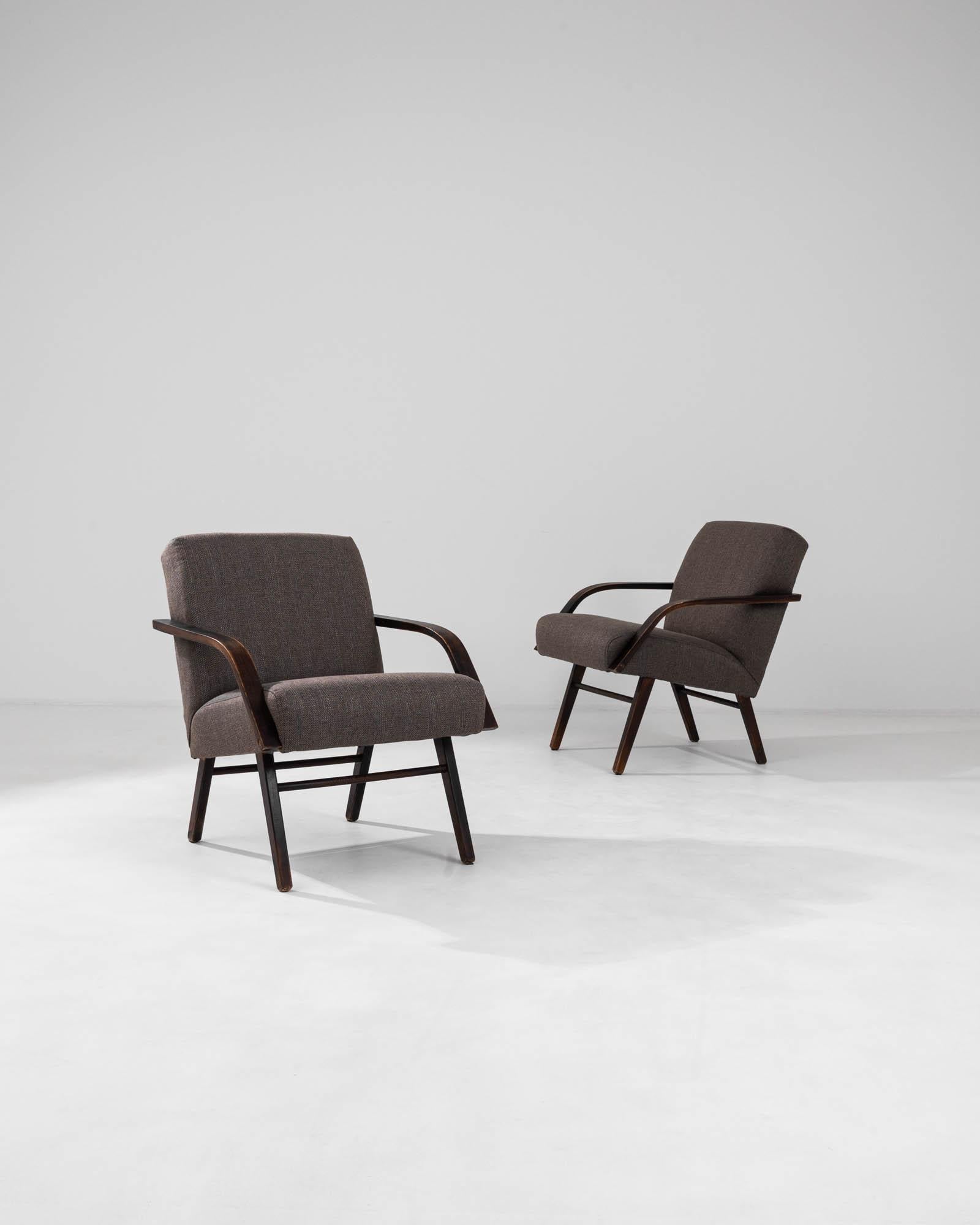Discover the seamless blend of comfort and mid-century modern design with this captivating pair of 1960s Czech armchairs by TON. These iconic pieces exhibit a streamlined form, with frames crafted from richly stained wood that exudes warmth and