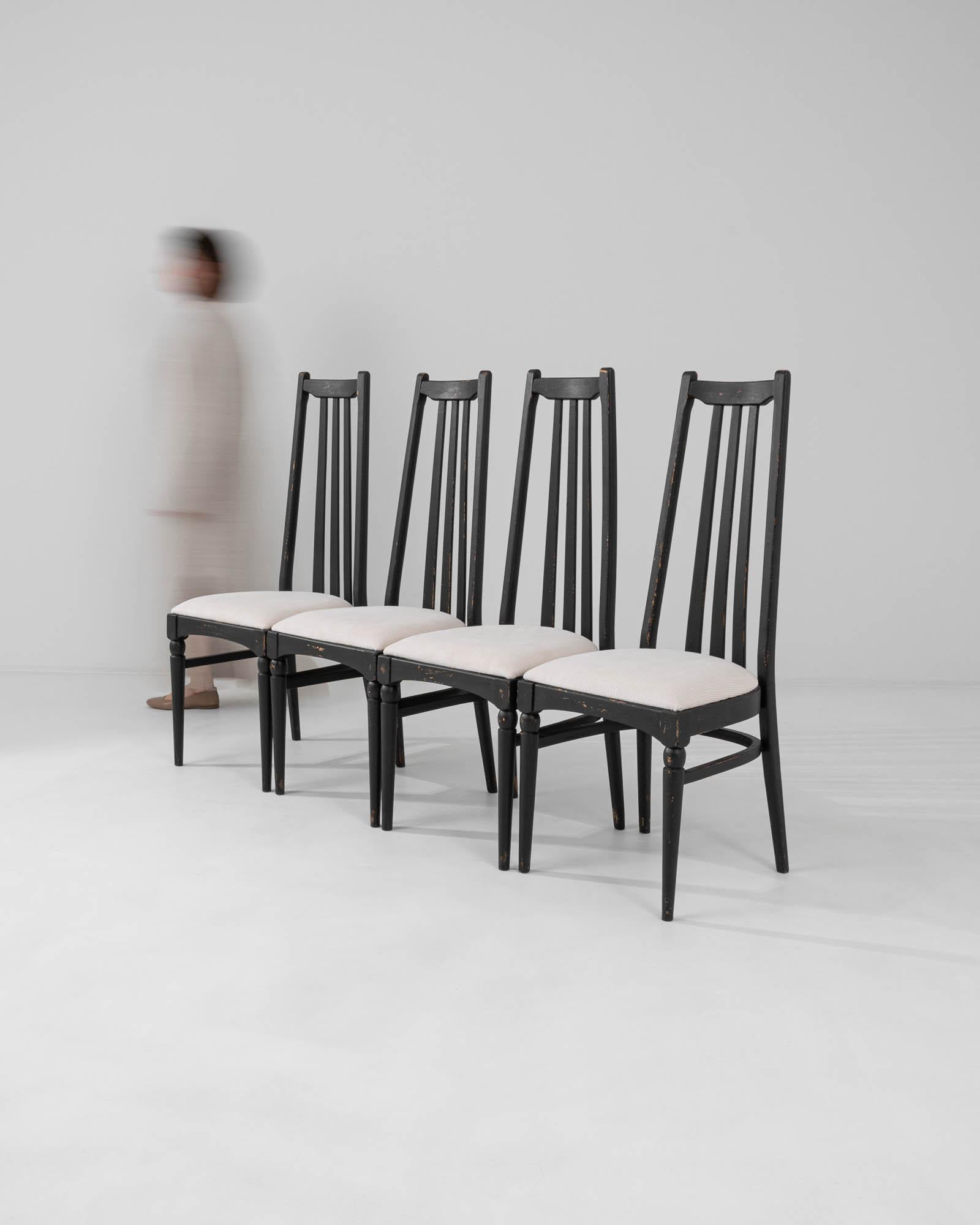 This set of four dining chairs, produced circa 1960 in Czechia, exudes a hint of gothic allure combined with mid-century modern style. The tall black backs, topped with minimalist finials resembling ears, and the sleek tapered legs, adorned with