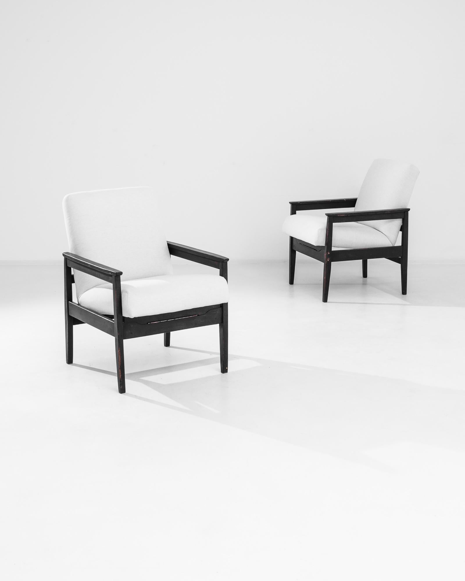Graphic and sophisticated, this pair of vintage armchairs possess a unique Modernist silhouette. Made in the former Czechoslovakia in the 1960s, a floating seat hangs at a reclined angle between the clean lines of the rectilinear frame. The cushions