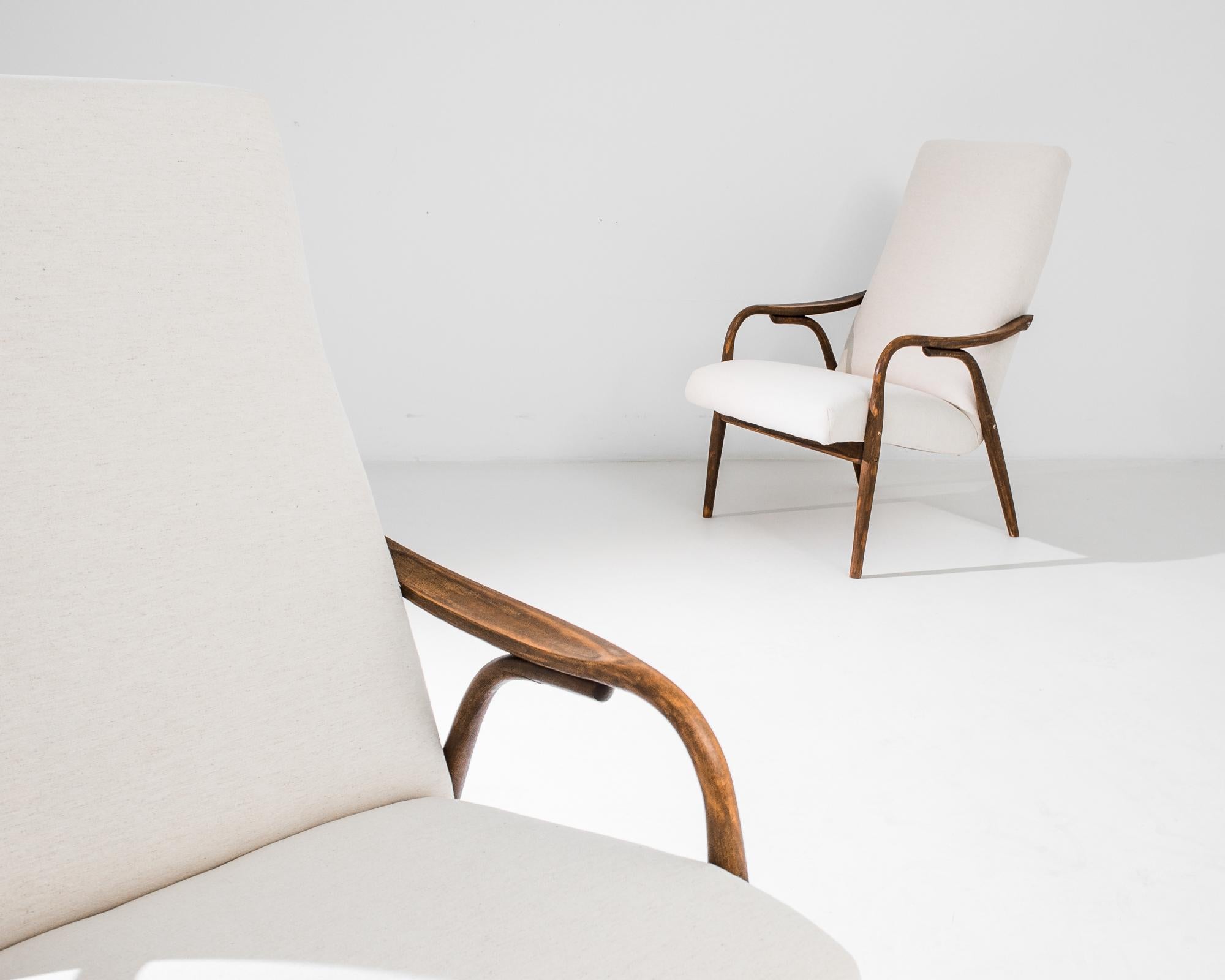 Introduce a touch of mid-century charm to your space with this elegant pair of 1960s Czech Wooden Armchairs. These armchairs showcase a seamless blend of form and function, featuring sleek, curved wooden frames that exhibit the meticulous