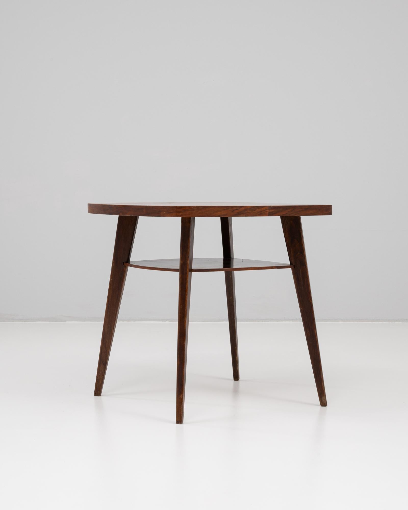 This 1960s Czech wooden side table by Jindřich Halabala exemplifies his signature blend of modernist function and elegant form. Featuring a circular top and a lower tier for additional storage or display, the table stands on four gently tapered legs