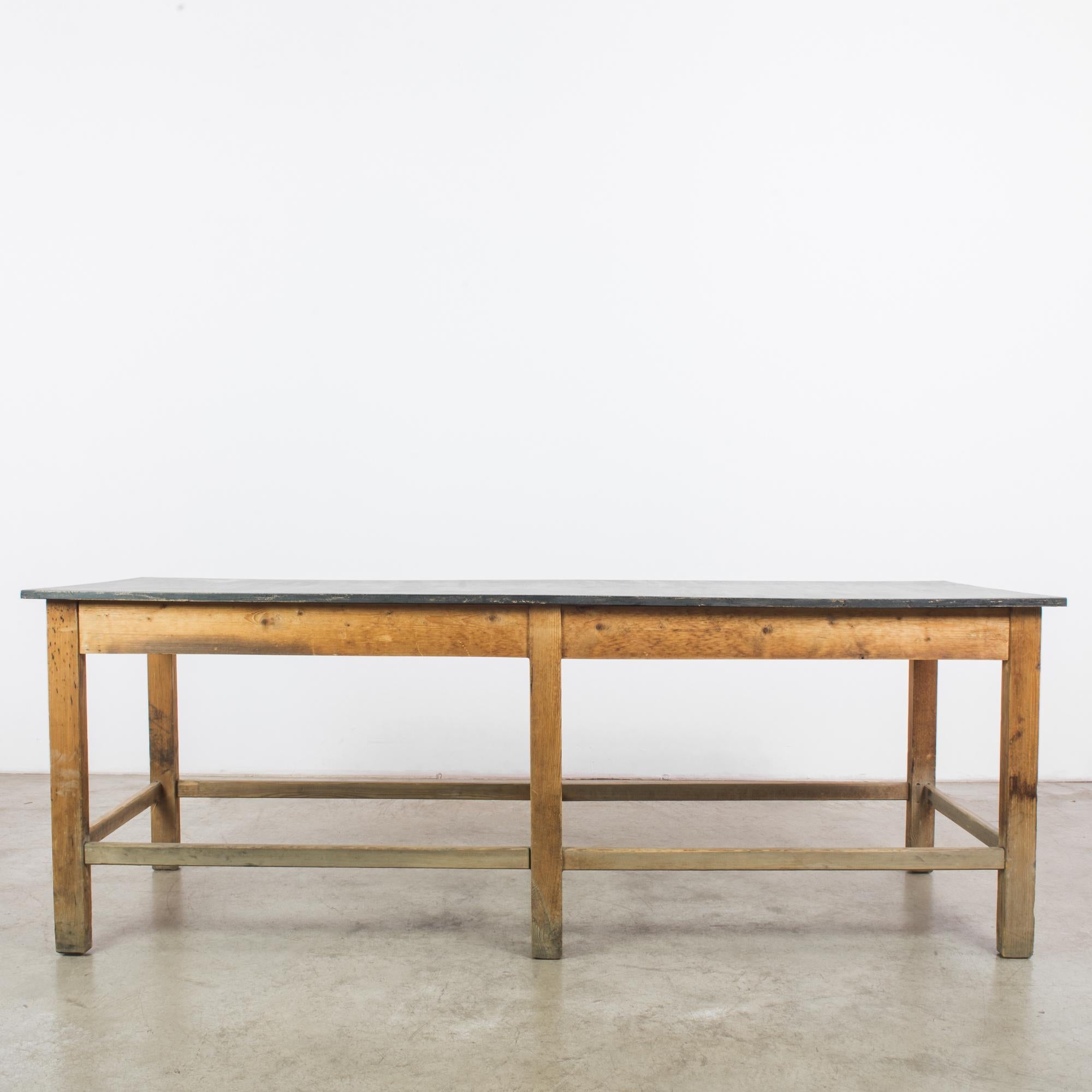 A wooden table from Czechia, circa 1960. Understated and stylish. The right-angled frame creates a grid-like, industrial aesthetic, warmed by the bright honeyed tone of the wood. The black paint of the tabletop has weathered with age, lending the