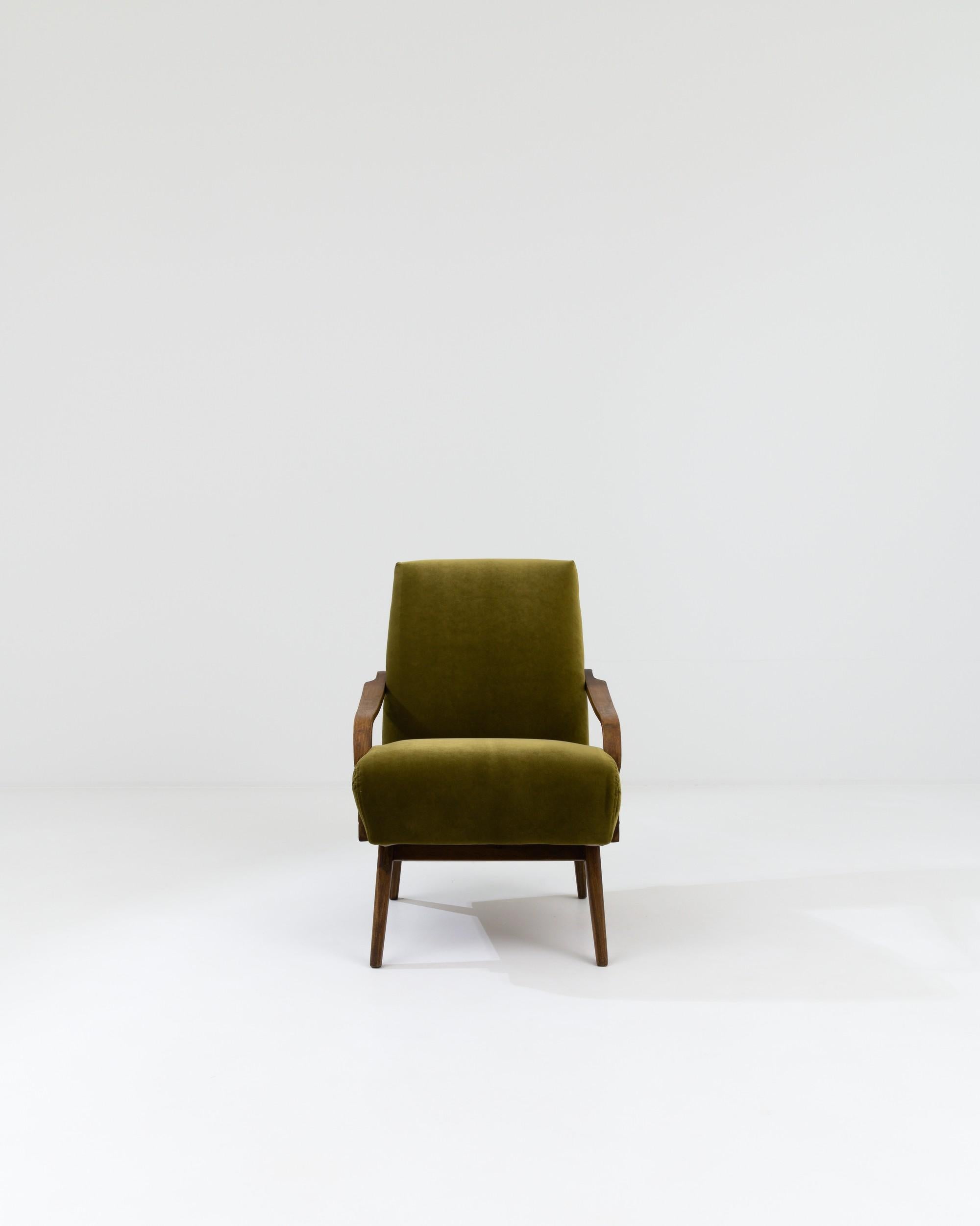 A wooden upholstered armchair created in 1960s Czechia. Characteristic of mid-century modern Czech design, this suave, high-backed armchair imparts a soothing sense of relaxation through understated and delicately executed craftsmanship. Carefully