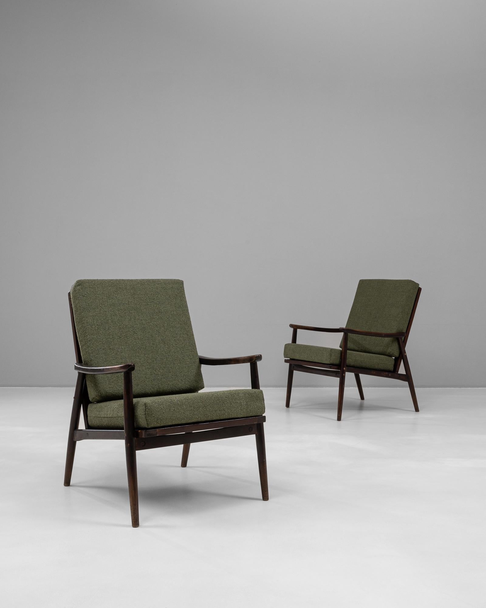 This pair of upholstered armchairs from 1960s Czechia captures the essence of mid-century modern design with their clean lines and functional elegance. Constructed with a solid wooden frame, the rich, dark-stained finish is complemented by the green