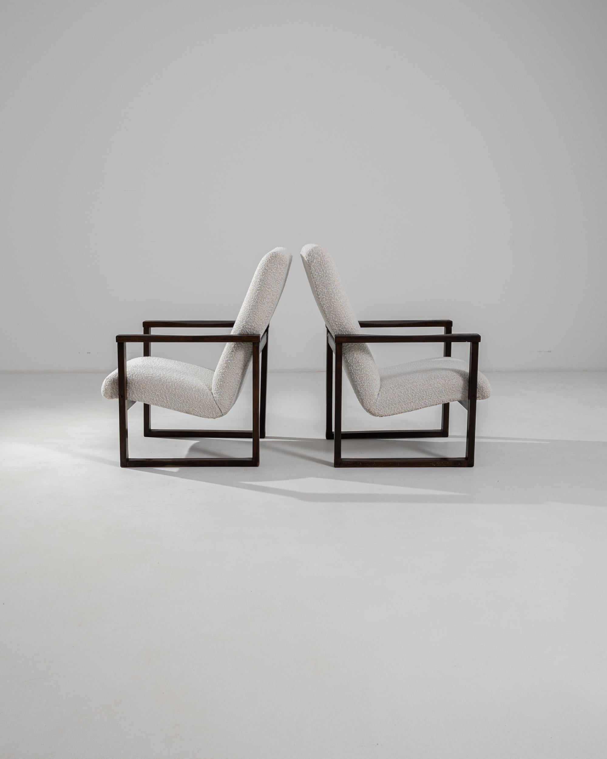 The graphic silhouette of this pair of vintage Modernist armchairs makes a striking impression. Made in Czechia in the 20th century, a cushioned seat appears to float weightlessly between two perfectly square frames of polished wood. This ingenious