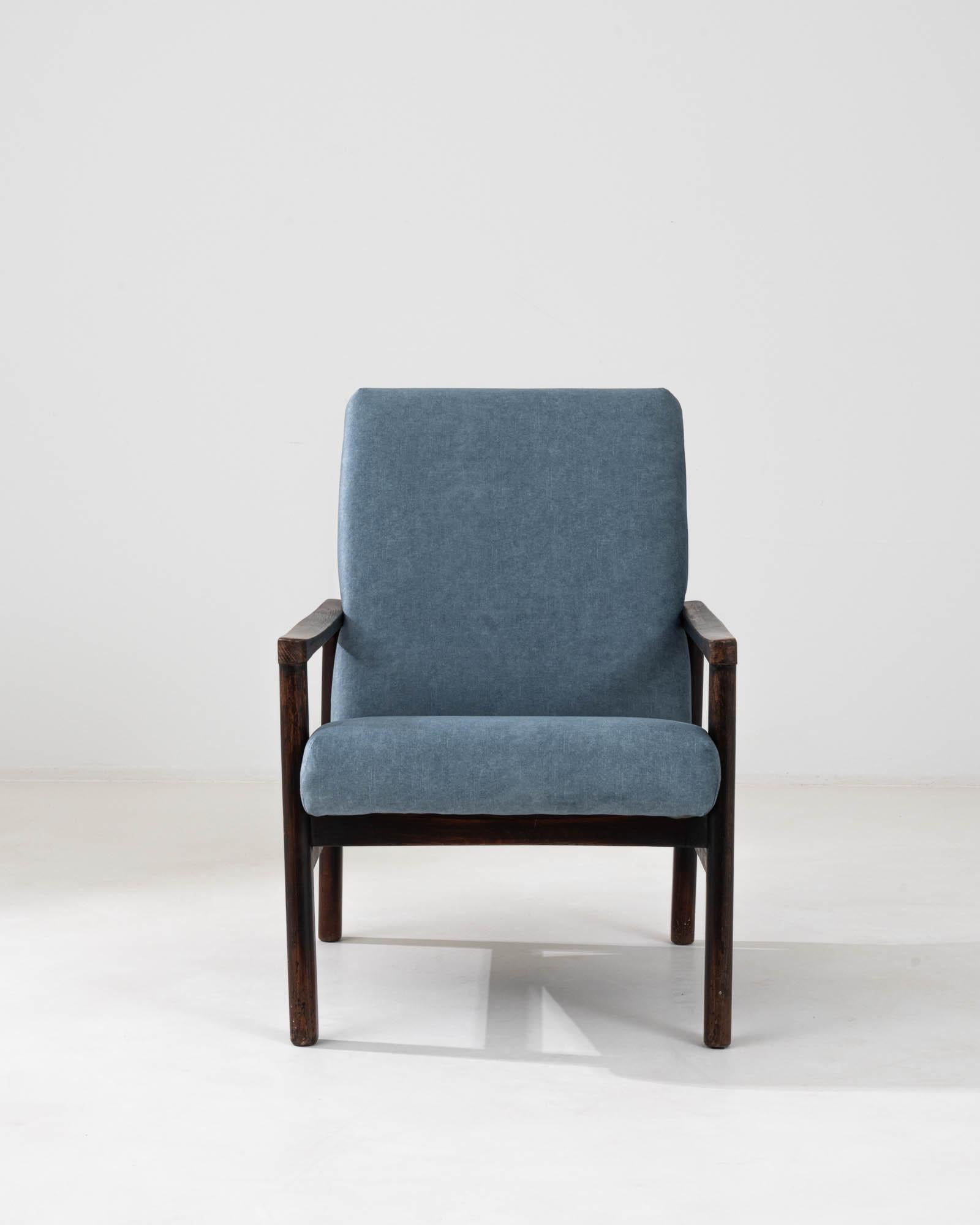 This 1960s Czech upholstered armchair is a testament to the art of timeless design, combining comfort and elegance. The chair features a solid wooden frame with a deep, rich patina that exudes the perfect balance of strength and style. Its sweeping