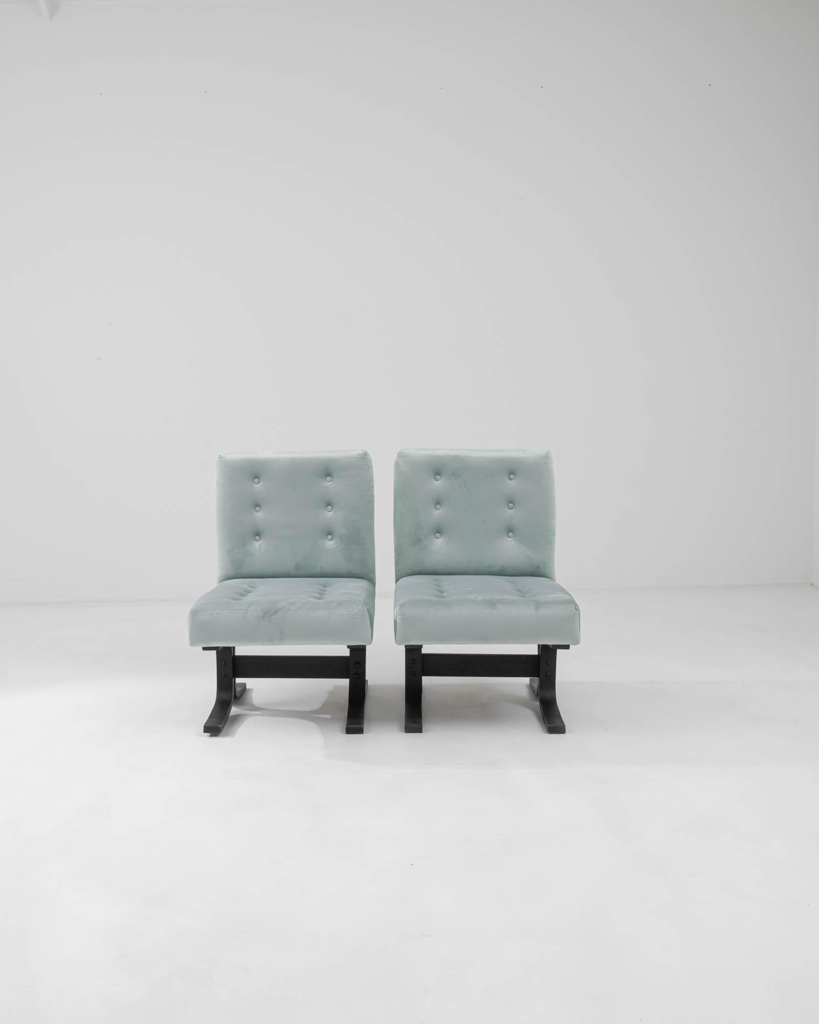This antique set features two 1960s Czechia Upholstered Chairs by Ludvik Volak, epitomizing mid-century modern design. The soft, sky-blue hue of the upholstery exudes timeless elegance. Crafted with precision, the black stands, with a distinctive