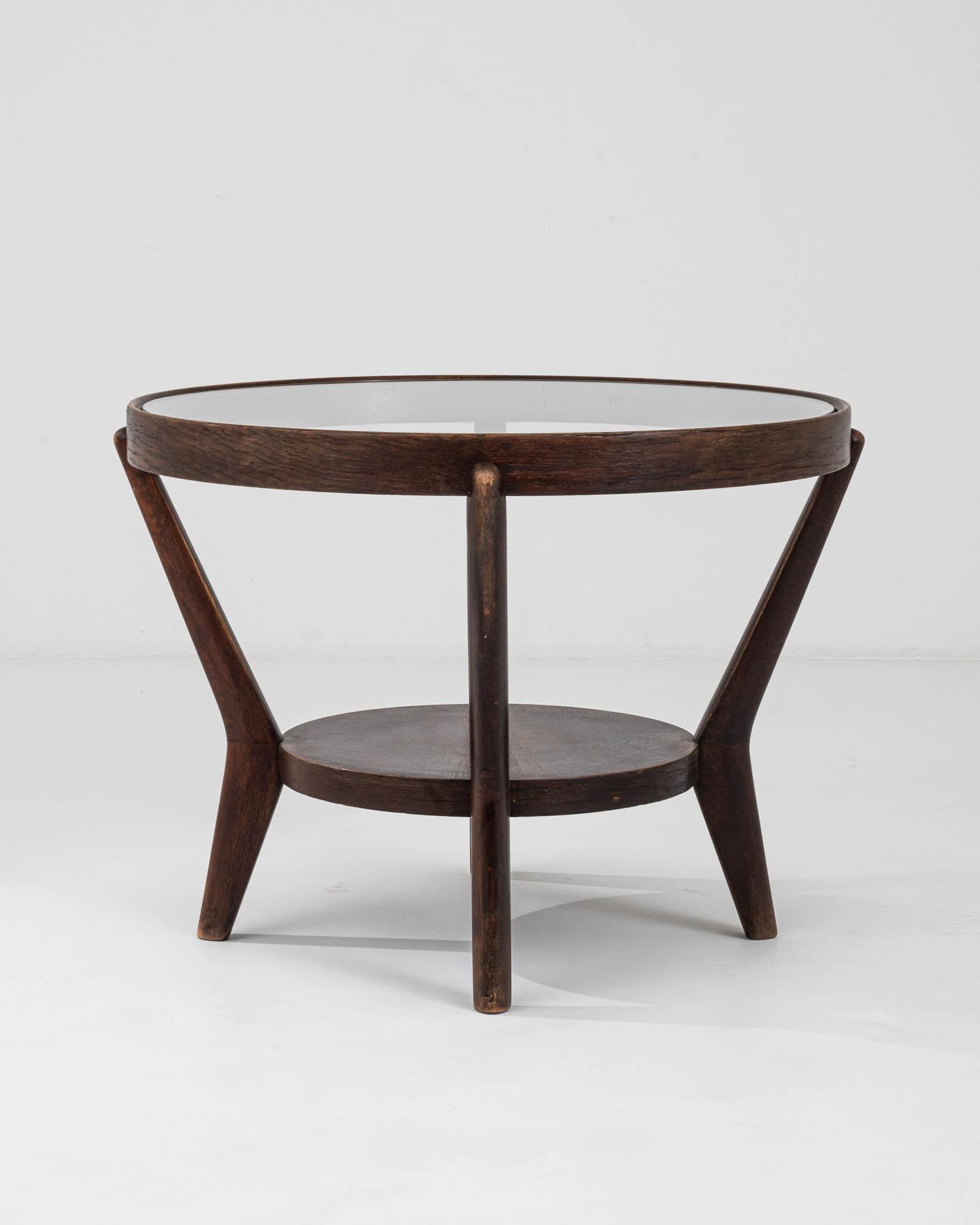 Cette table basse tchèque en bois des années 1960, conçue par K.Kozelkka & A.Kropacek, est un bel exemple de design moderne du milieu du siècle dernier. Son plateau en verre circulaire repose gracieusement sur un cadre en bois riche et foncé,