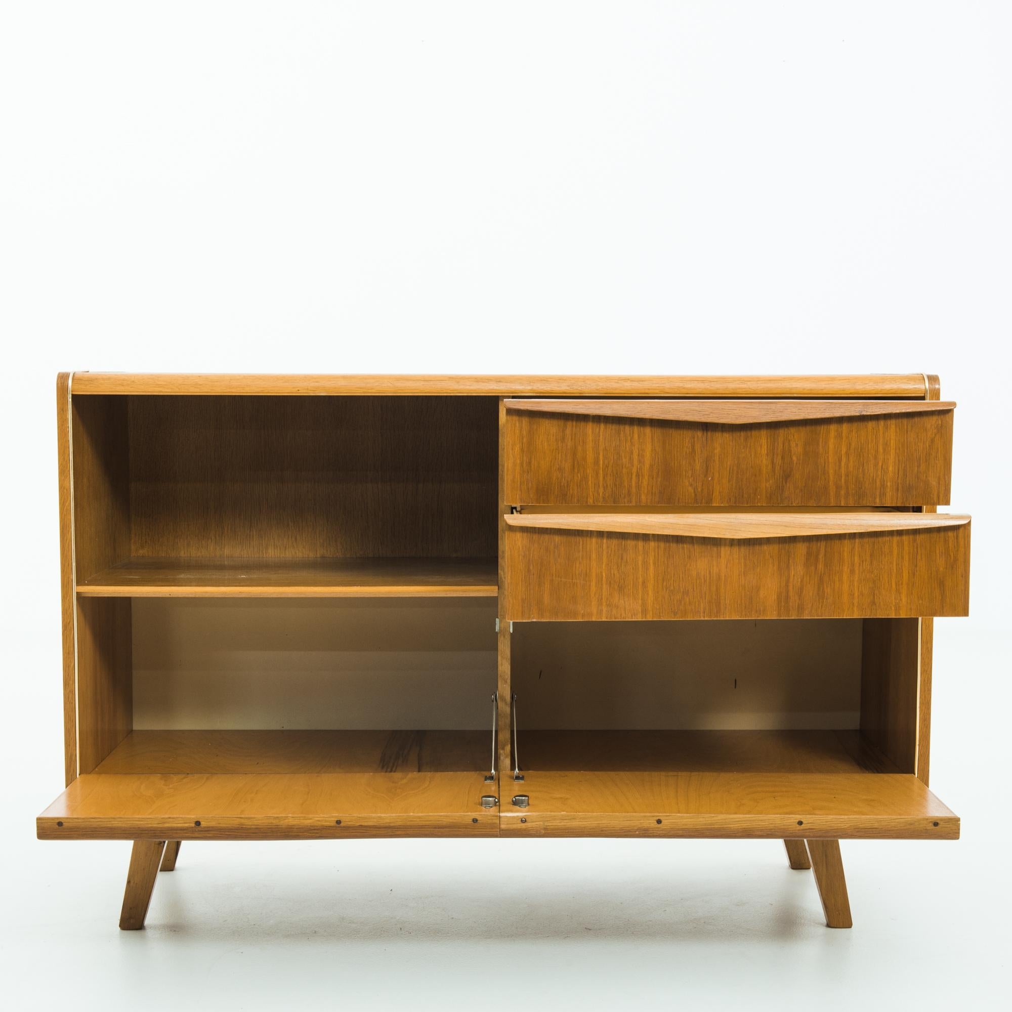 Thoughtfully crafted during the vibrant era of the 1960s in Czechia, this wooden sideboard epitomizes the fusion of sleek modern design and traditional craftsmanship. Constructed from high-quality wood, likely oak or beech, this sideboard showcases