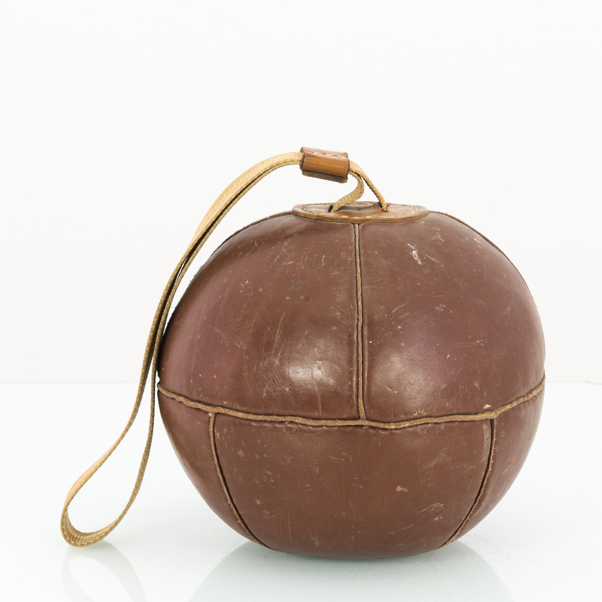 This boxing ball was made in the former Czechoslovakia, circa 1960. The ball can be suspended from a strap attached to the top. With its handcrafted panels displaying a timeworn patina, this piece will inject the spirit and intensity of boxing
