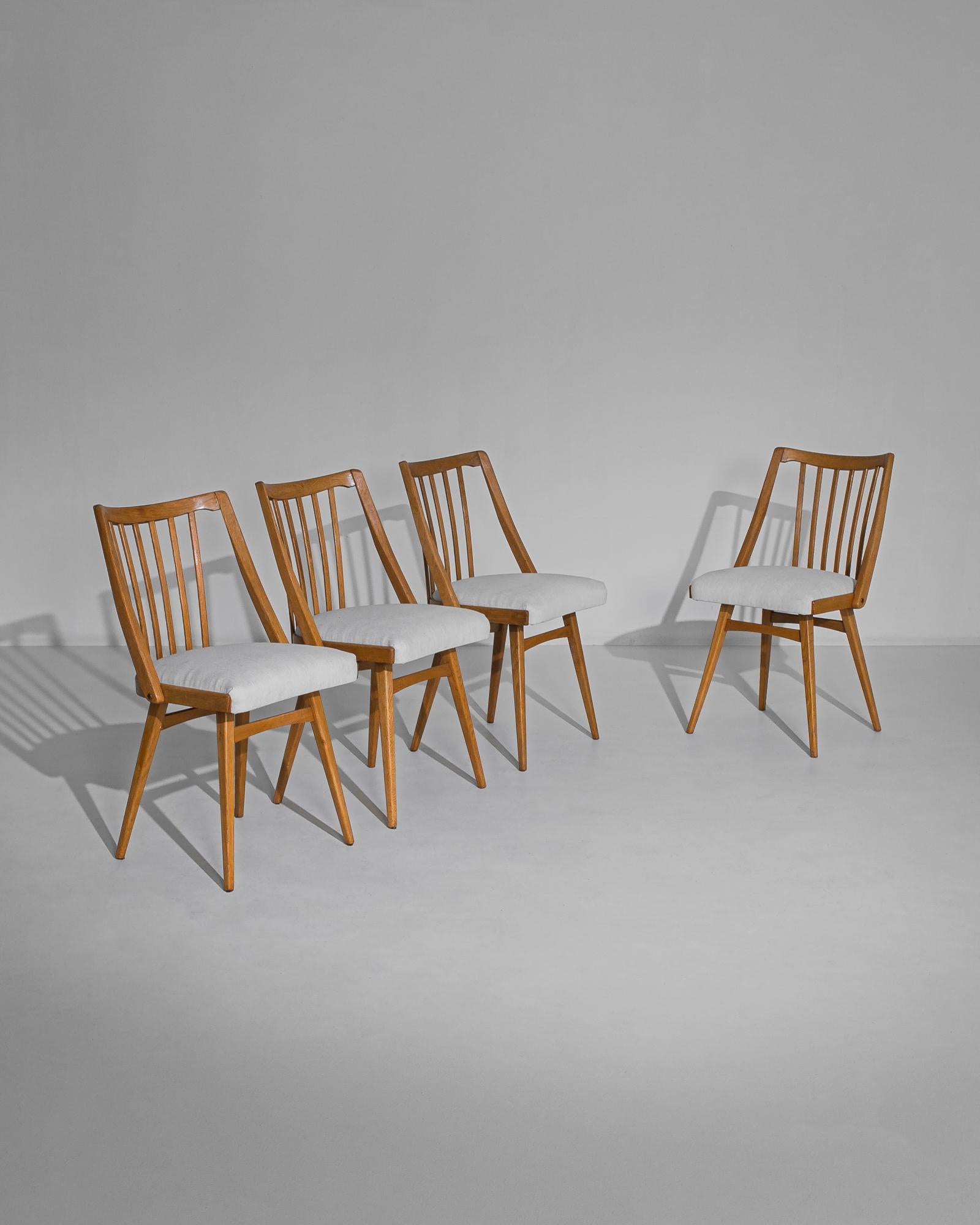This set of four wooden dining chairs was made in the former Czechoslovakia, circa 1960. The splayed legs and subtle arcs of the top rails and stiles give the chairs an elegant silhouette. A slatted back enhances the streamlined design. Recently