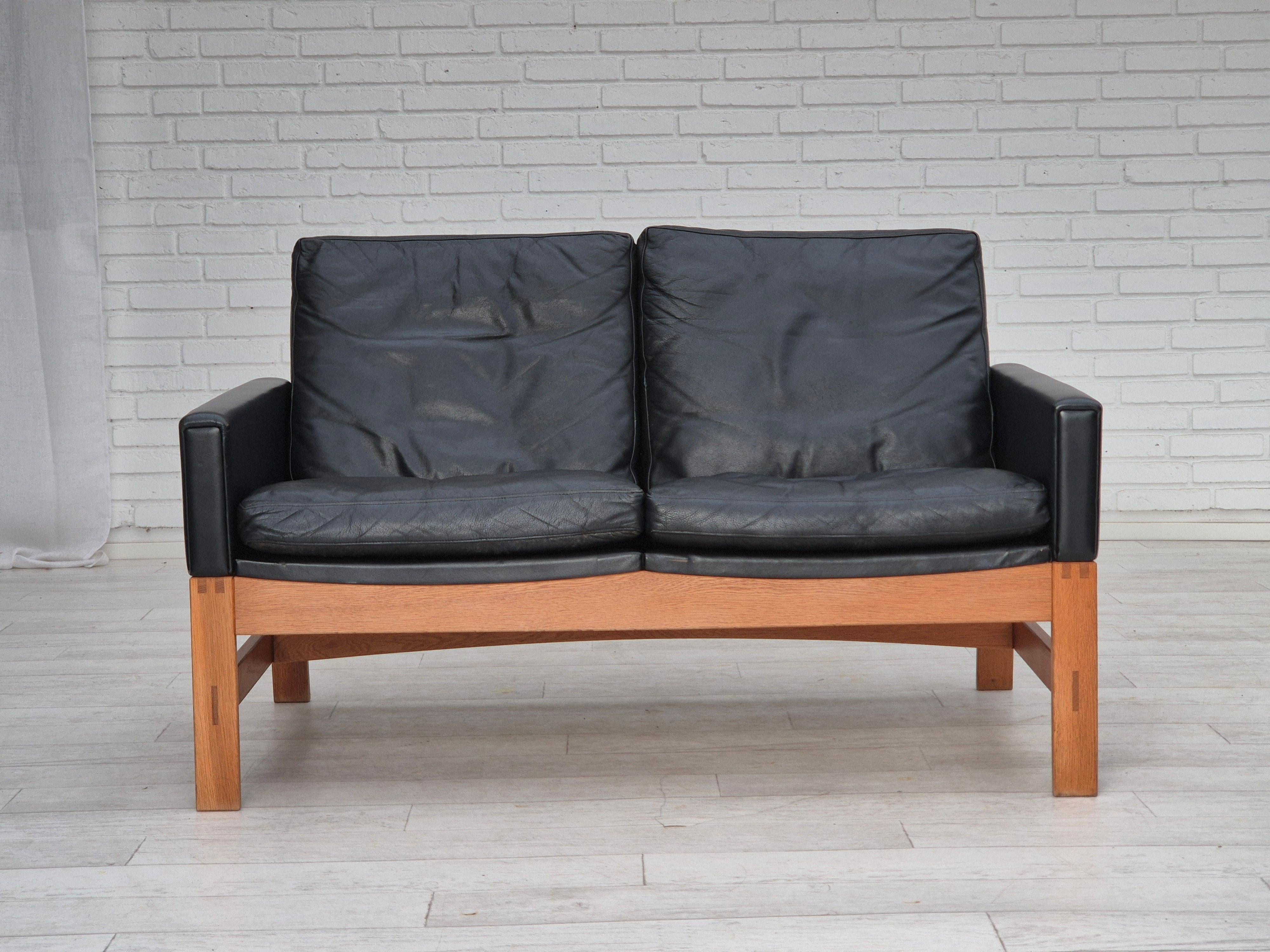 1960er Jahre, dänisches 2-Sitzer-Sofa in sehr gutem Originalzustand: keine Gerüche, keine Flecken und stabile Konstruktion. Original schwarzes Möbelleder, massives Eichenholz. Hergestellt von einem dänischen Möbelhersteller etwa in den 1960-65er