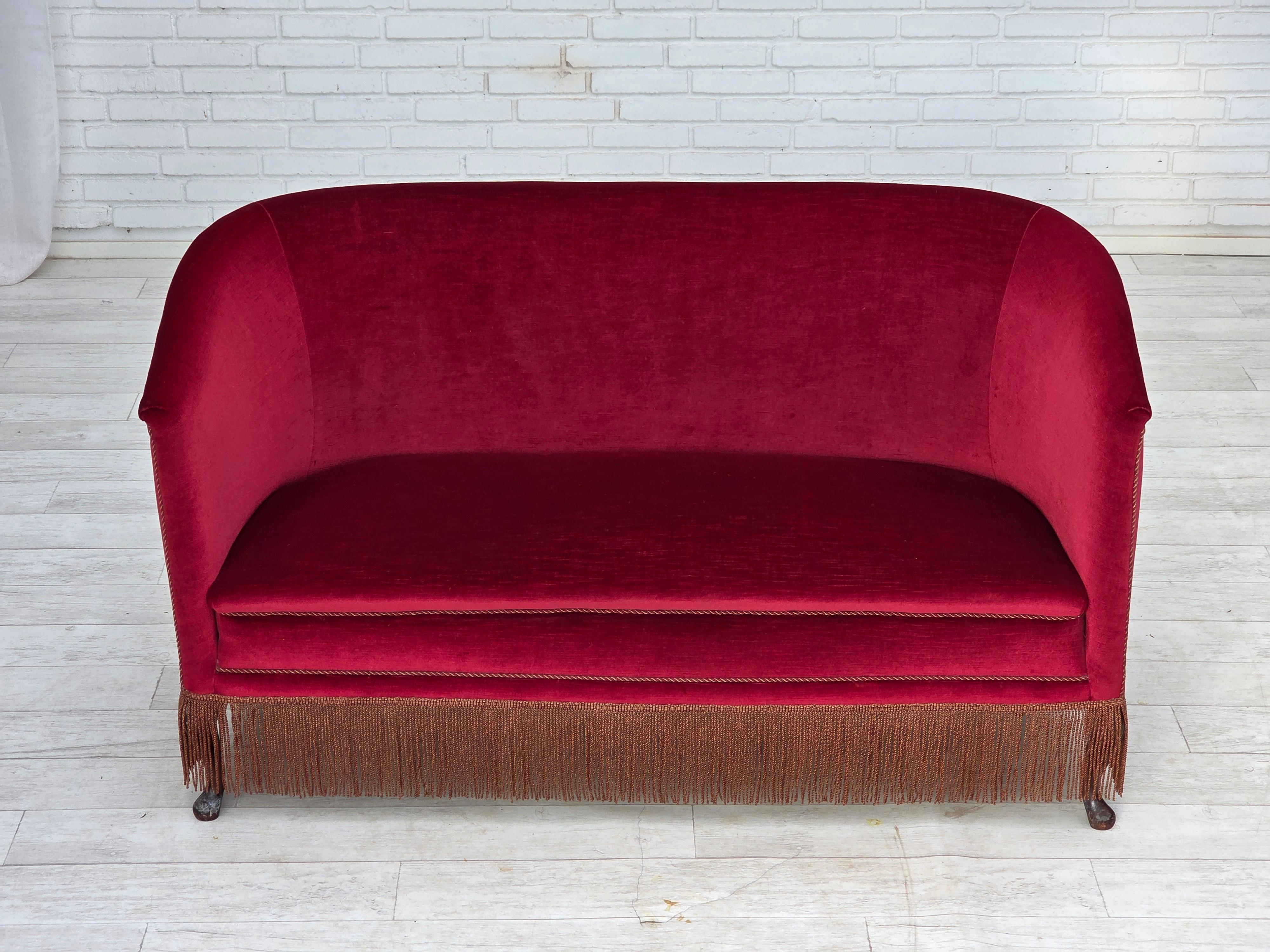 Divano danese a 2 posti degli anni '60. Velluto rosso da arredamento, gambe in legno di frassino, molle in ottone nella seduta. Il divano è stato tappezzato da un artigiano circa 15 anni fa. Buone condizioni: nessun odore, nessuna macchia e