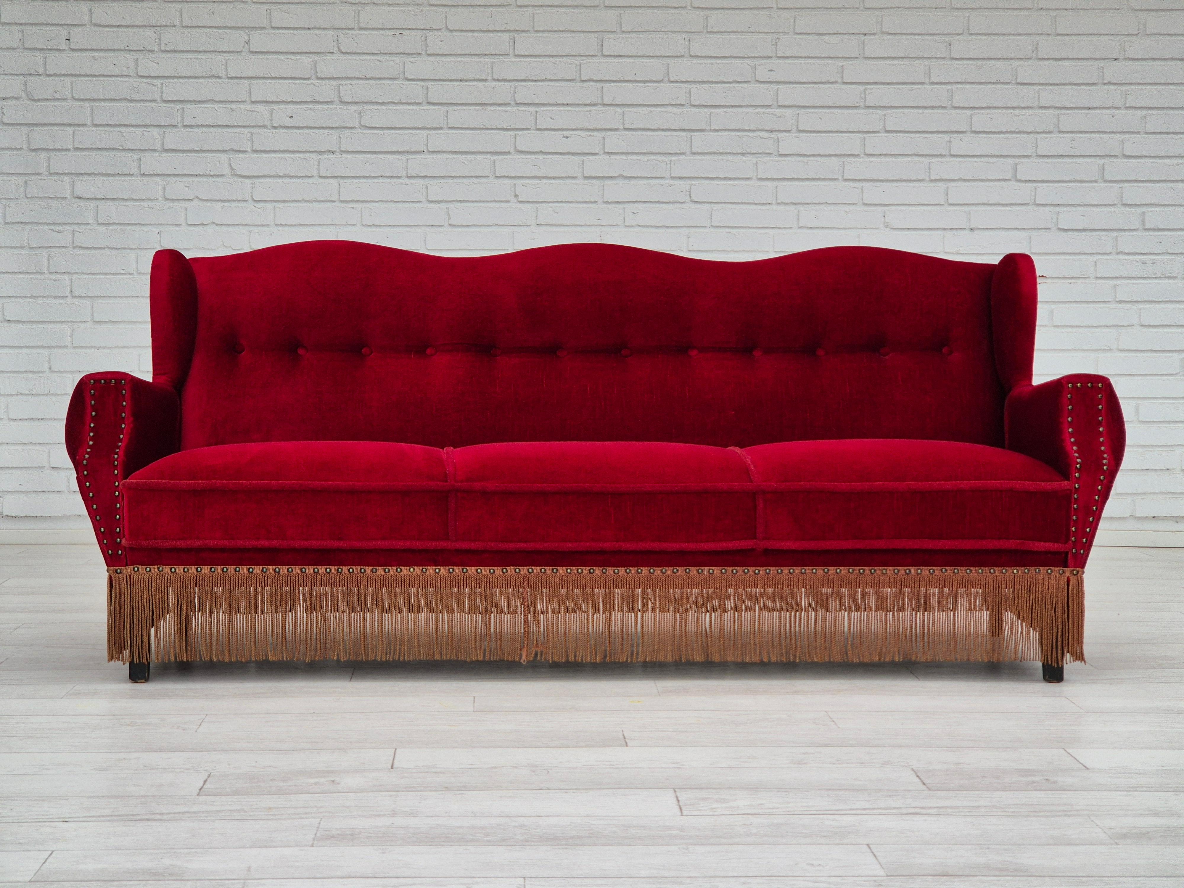 1960s, Danish 3 seater sofa in original very good condition: no smells and no stains. Cherry-red furniture velour, oak wood legs. Springs in the seat. Manufactured by Danish furniture manufacturer in about 1960s.