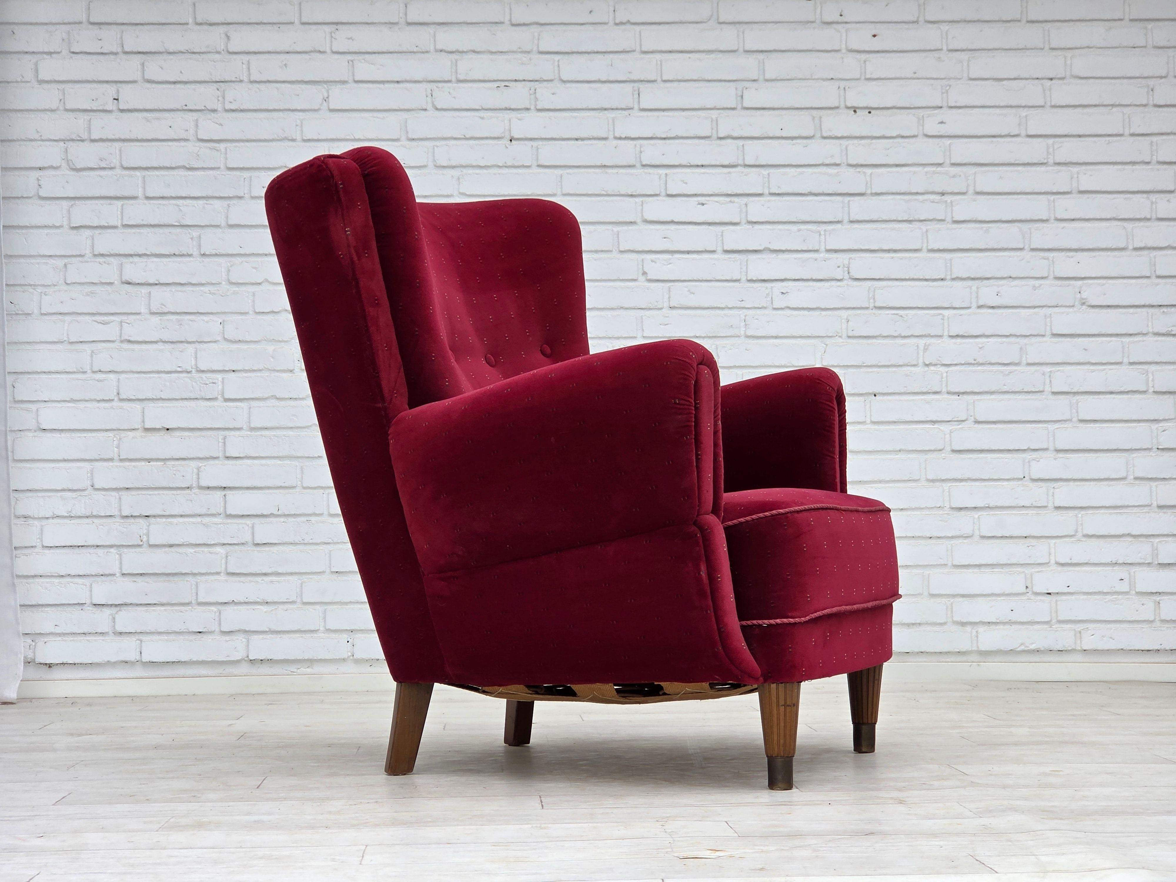 1960, Poltrona danese. Rivestito da un artigiano circa 10-15 anni fa. Ottime condizioni: nessun odore, nessuna macchia e struttura stabile. Velluto da arredamento rosso ciliegia, gambe in legno di faggio con tasselli in ottone, molle in ottone nella